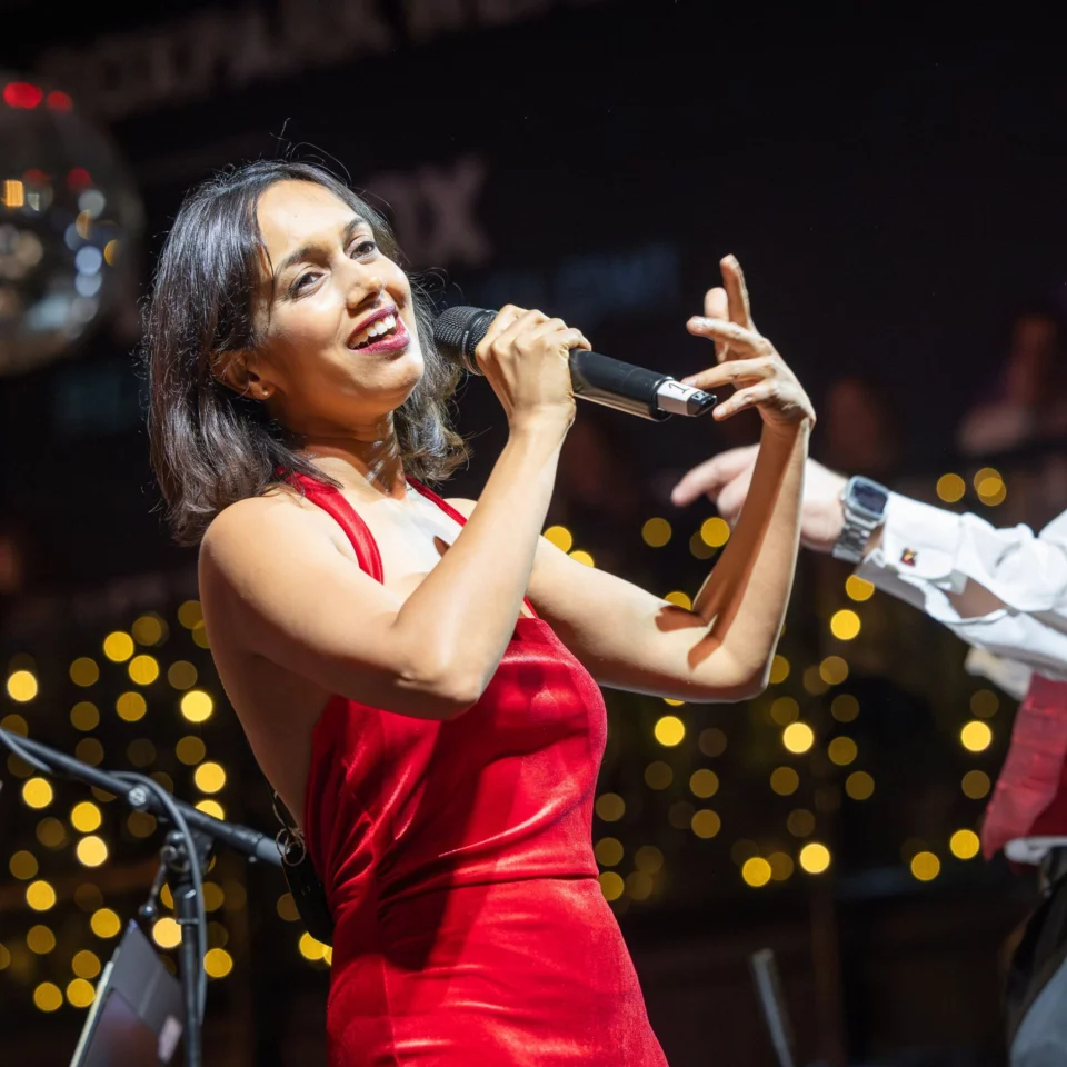 Sumudu Jayatilaka performing with the Royal Philharmonic Orchestra, singing with her arms outstretched
