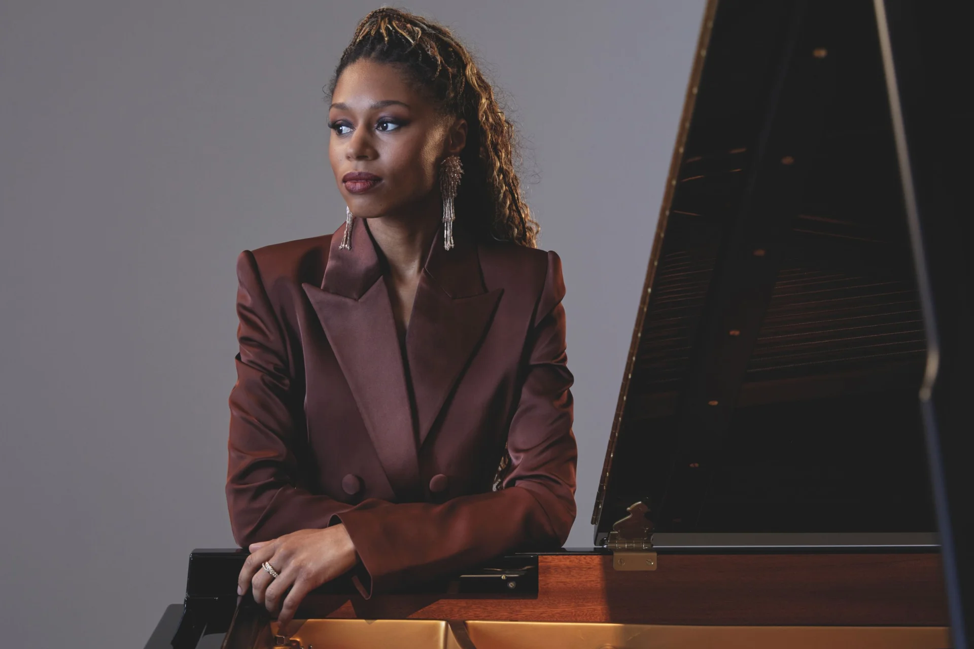 Isata Kanneh Mason stands leaning on a piano