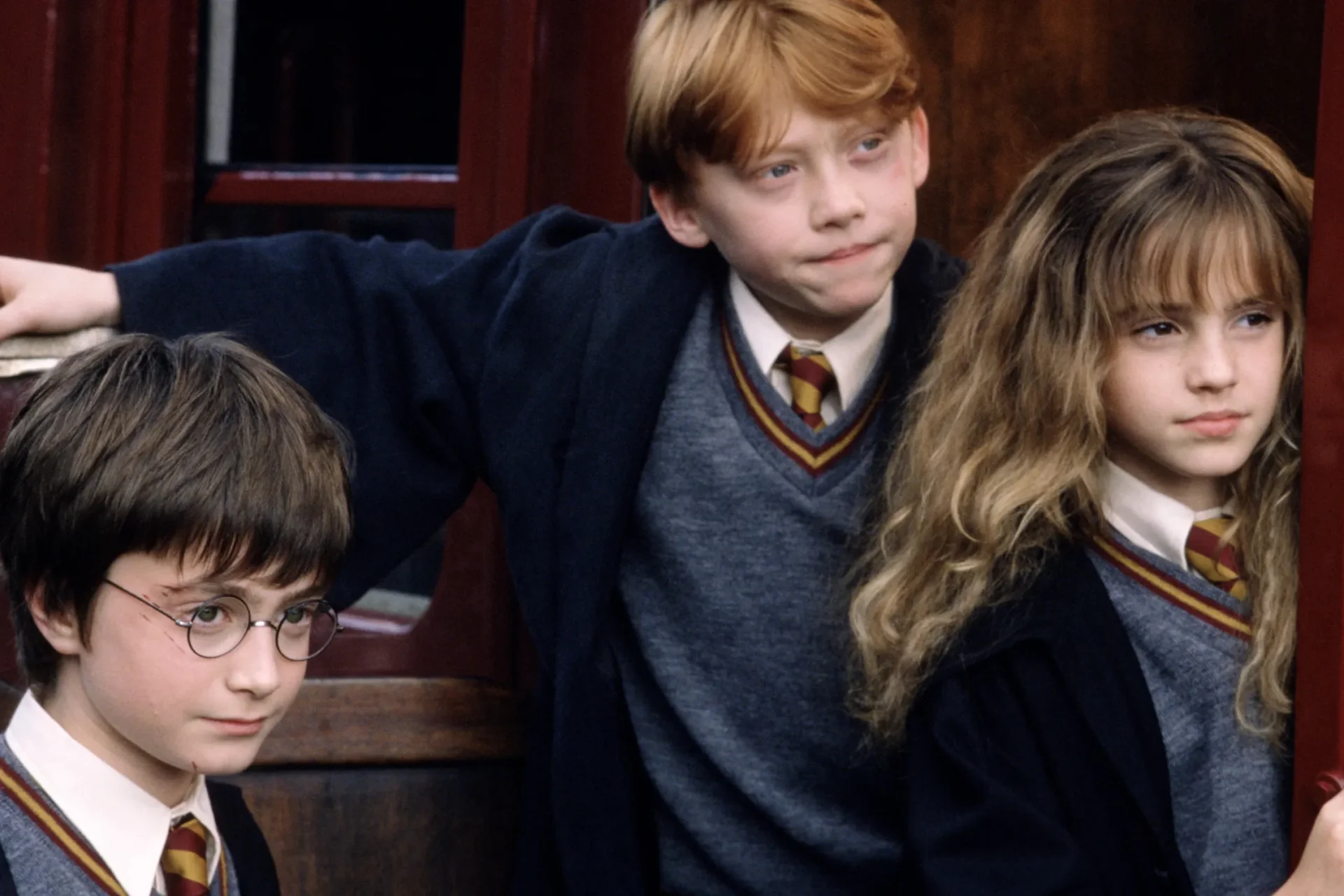 Harry Potter, Ron Weasley and Hermione Granger leaning against the Hogwarts Express