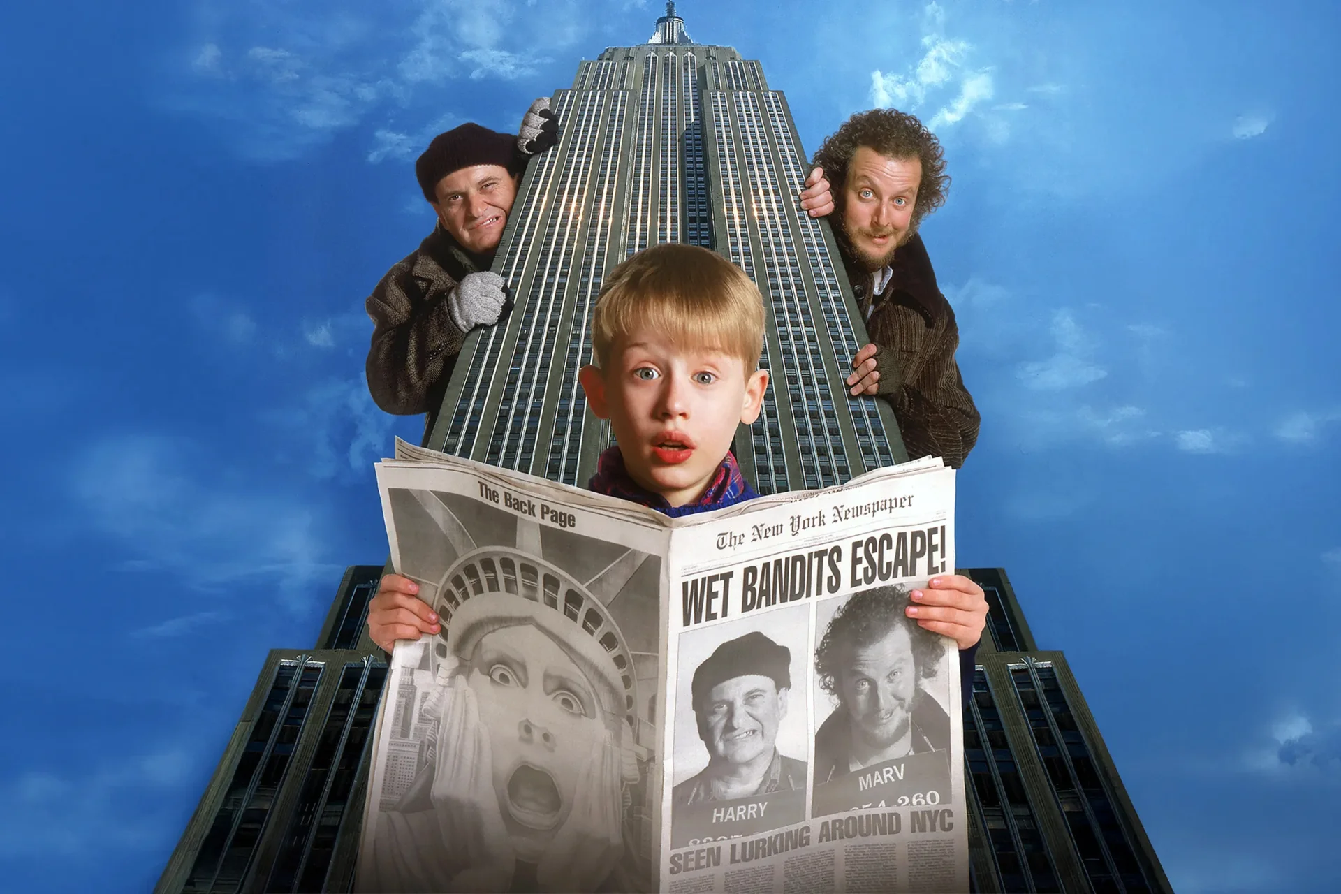 Home Alone's Kevin in front of the empire state building reading a newspaper with the 'Wet Bandets' looking at him round the corner artwork.