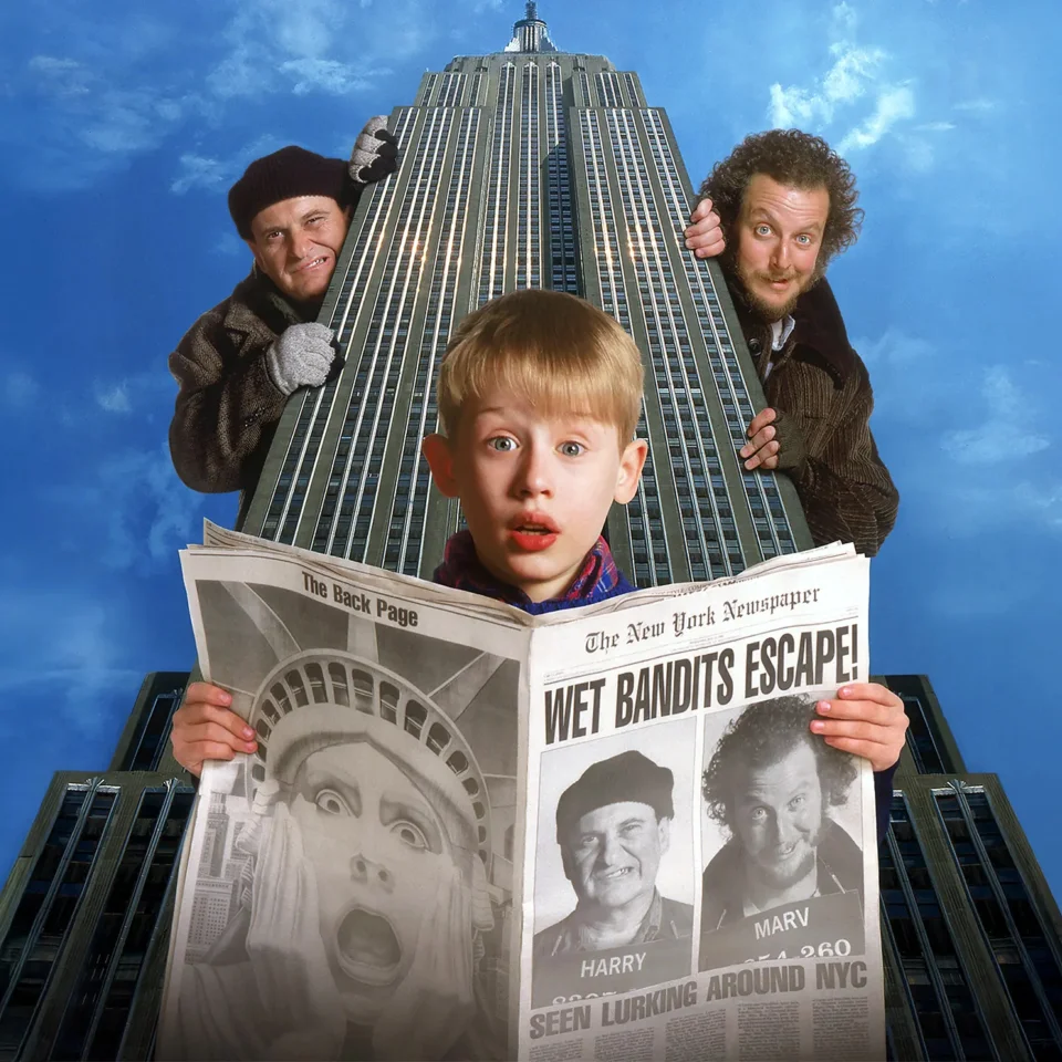 Home Alone's Kevin in front of the empire state building reading a newspaper with the 'Wet Bandets' looking at him round the corner artwork.