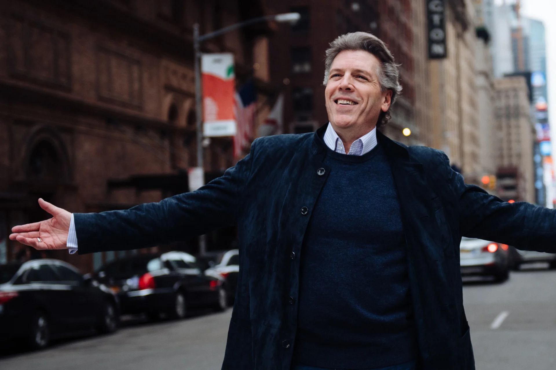 Baritone Thomas Hampson in the middle of a street stretching out his arms