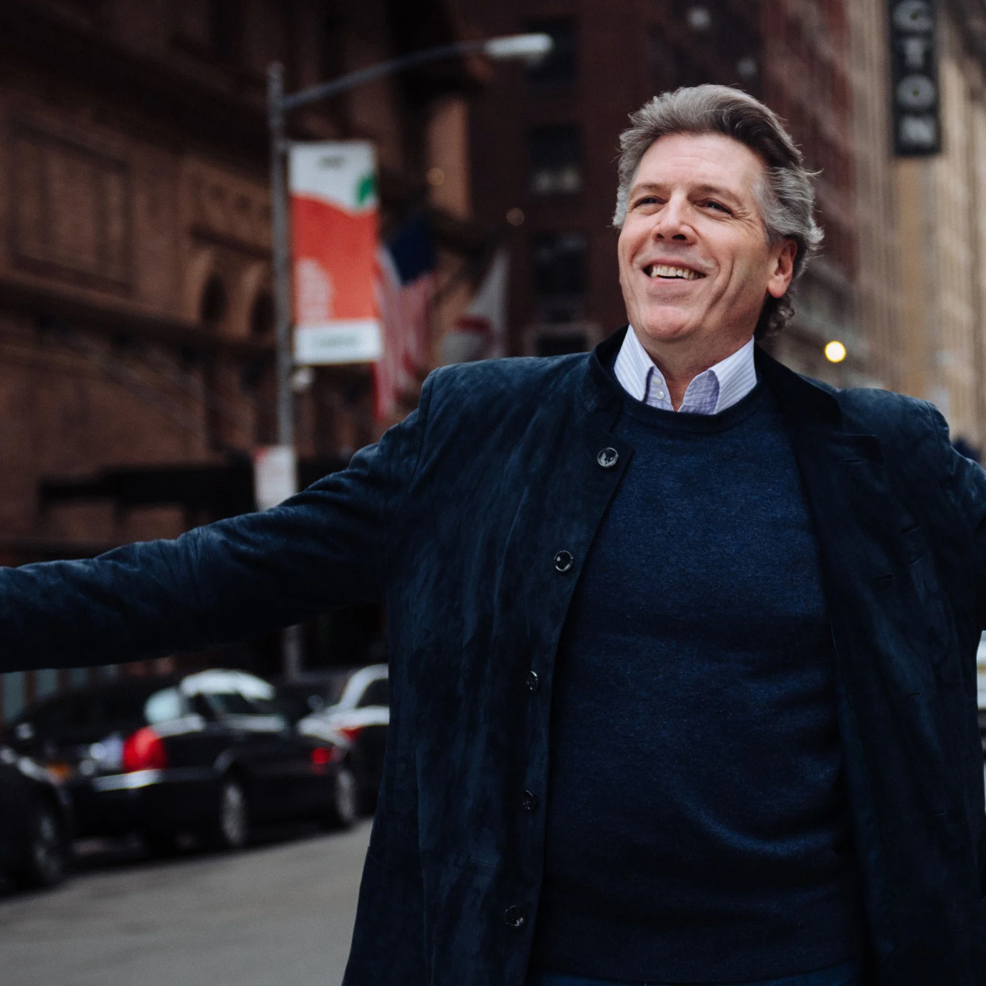 Baritone Thomas Hampson in the middle of a street stretching out his arms
