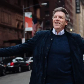 Baritone Thomas Hampson in the middle of a street stretching out his arms
