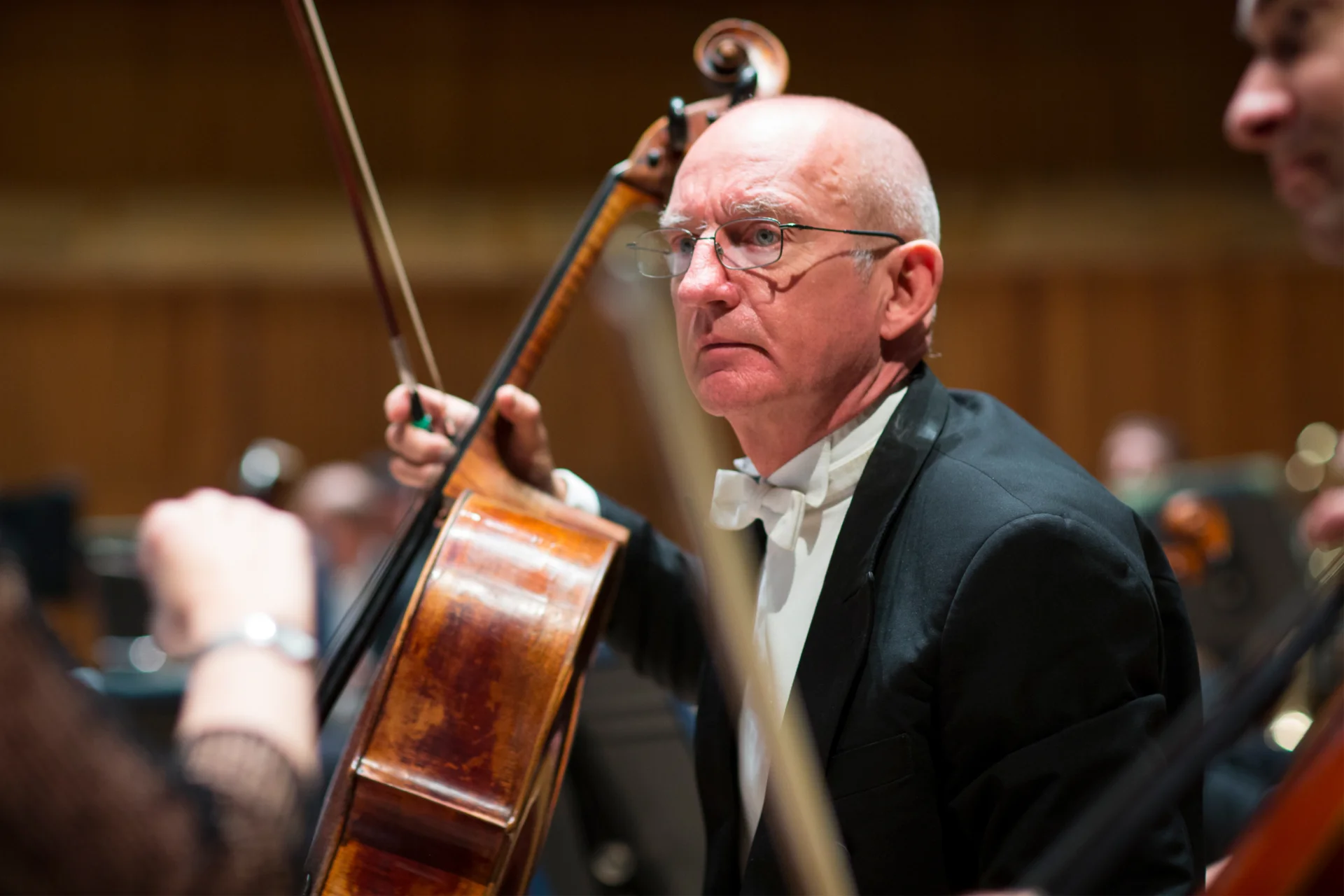Cellist Bill Heggart sitting and holding his cello in rehearsal