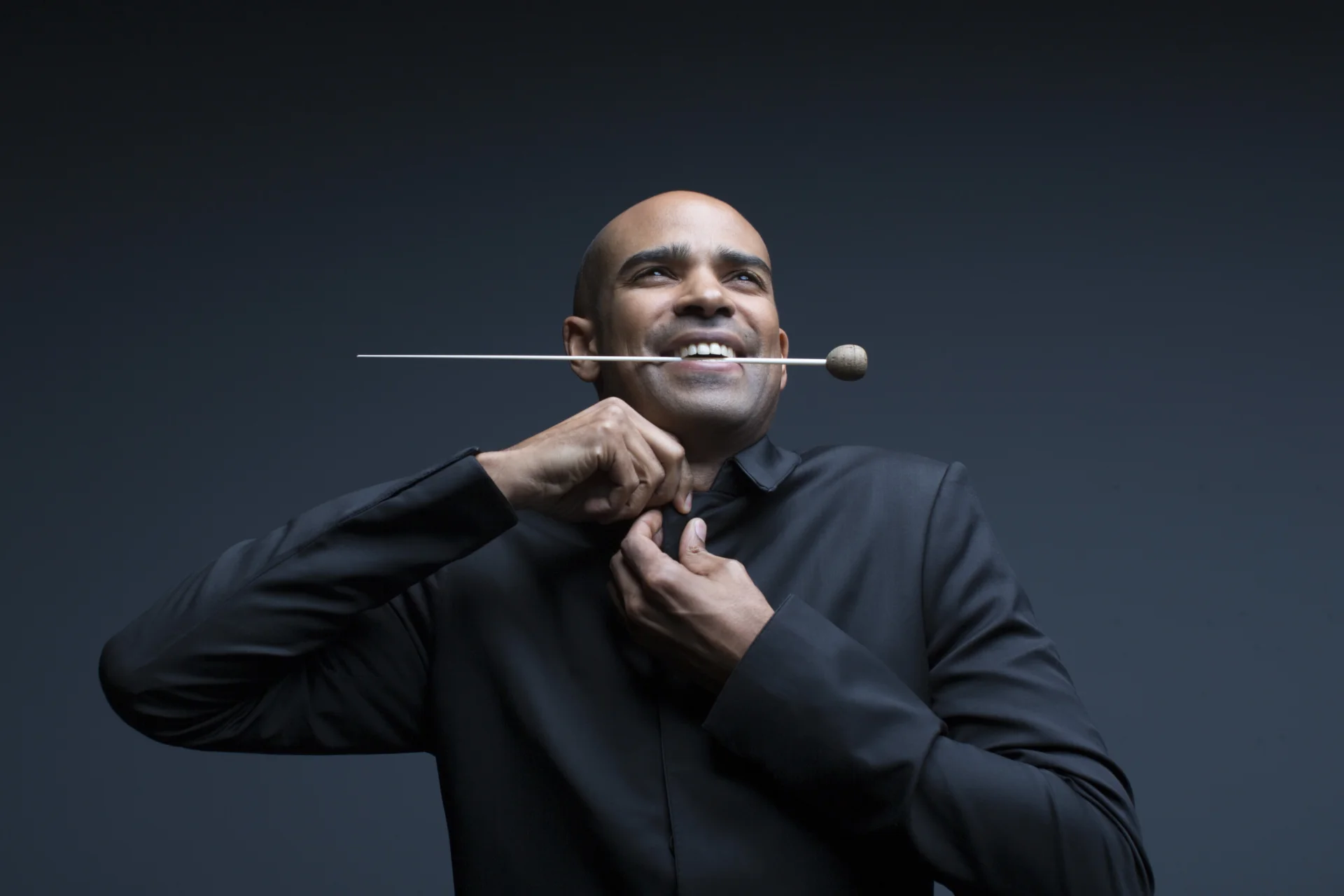 Kevin John Edusei doing up his tie with baton in mouth