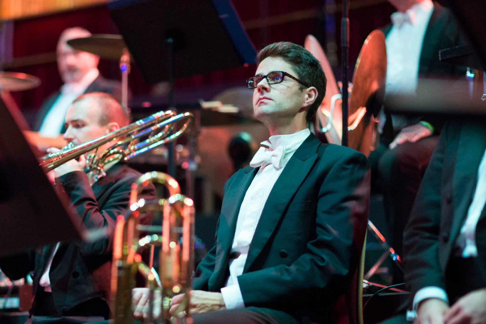 Rupert Whitehead sitting in orchestra wearing black suit jacket with white shirt and bow tie