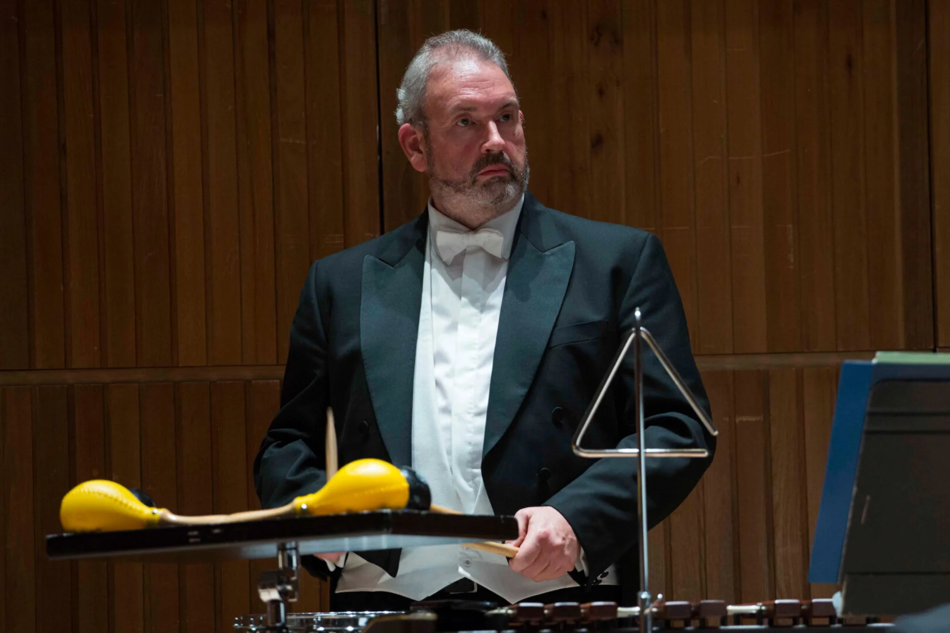 Stephen Quigley standing in Orchestra in black jacket and white shirt