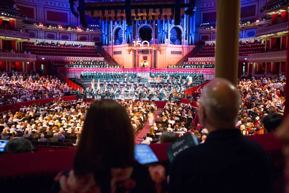 Audience members watching a concert from a box in the Royal Albert Hall