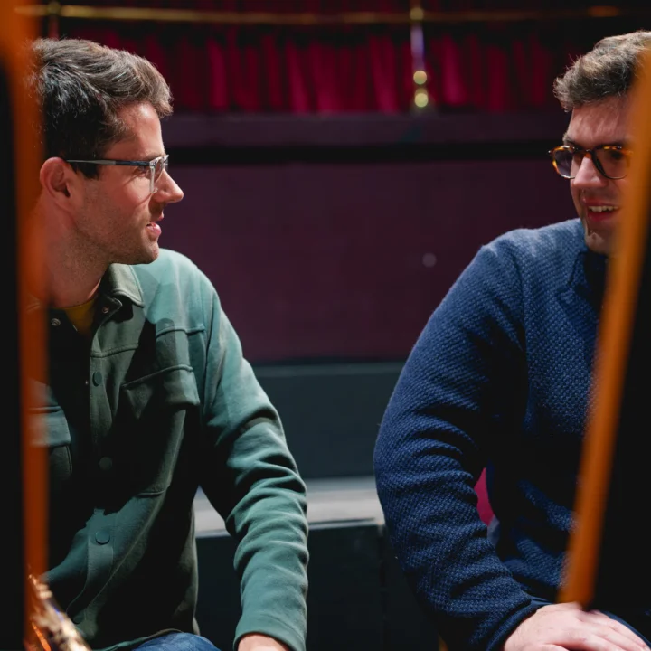 Two musicians talking partially obscured by music stands