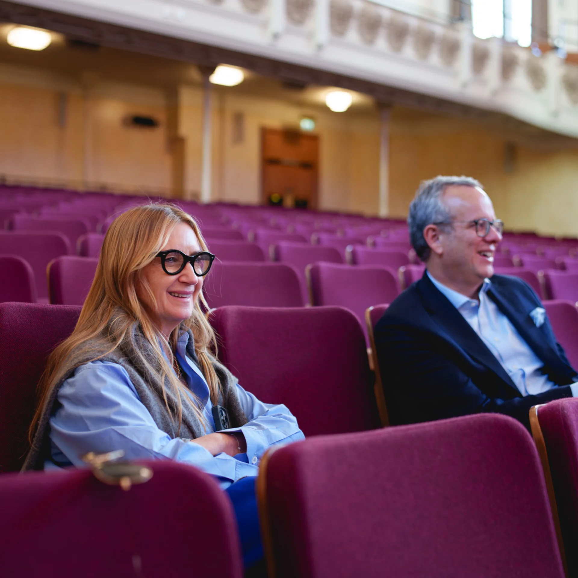 Anya Hindmarch and Michael Hayman in stall seats watching a rehearsal at Cadogan Hall and smiling