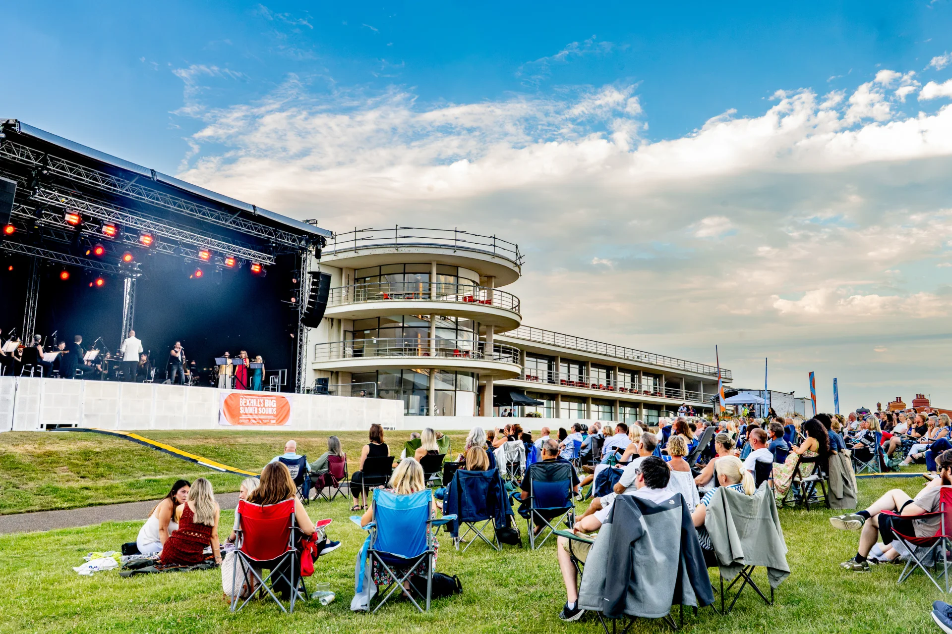 The RPO performing on an outdoor stage with the audience sitting on blankets and folding chairs on the greass