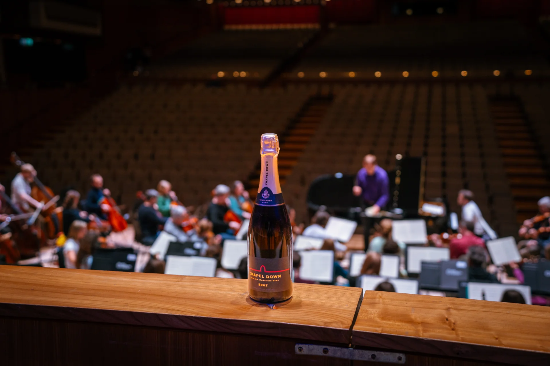 A bottle of Chapel Down wine on the choir seats ledge just behind and above the Orchestra rehearsing in the background