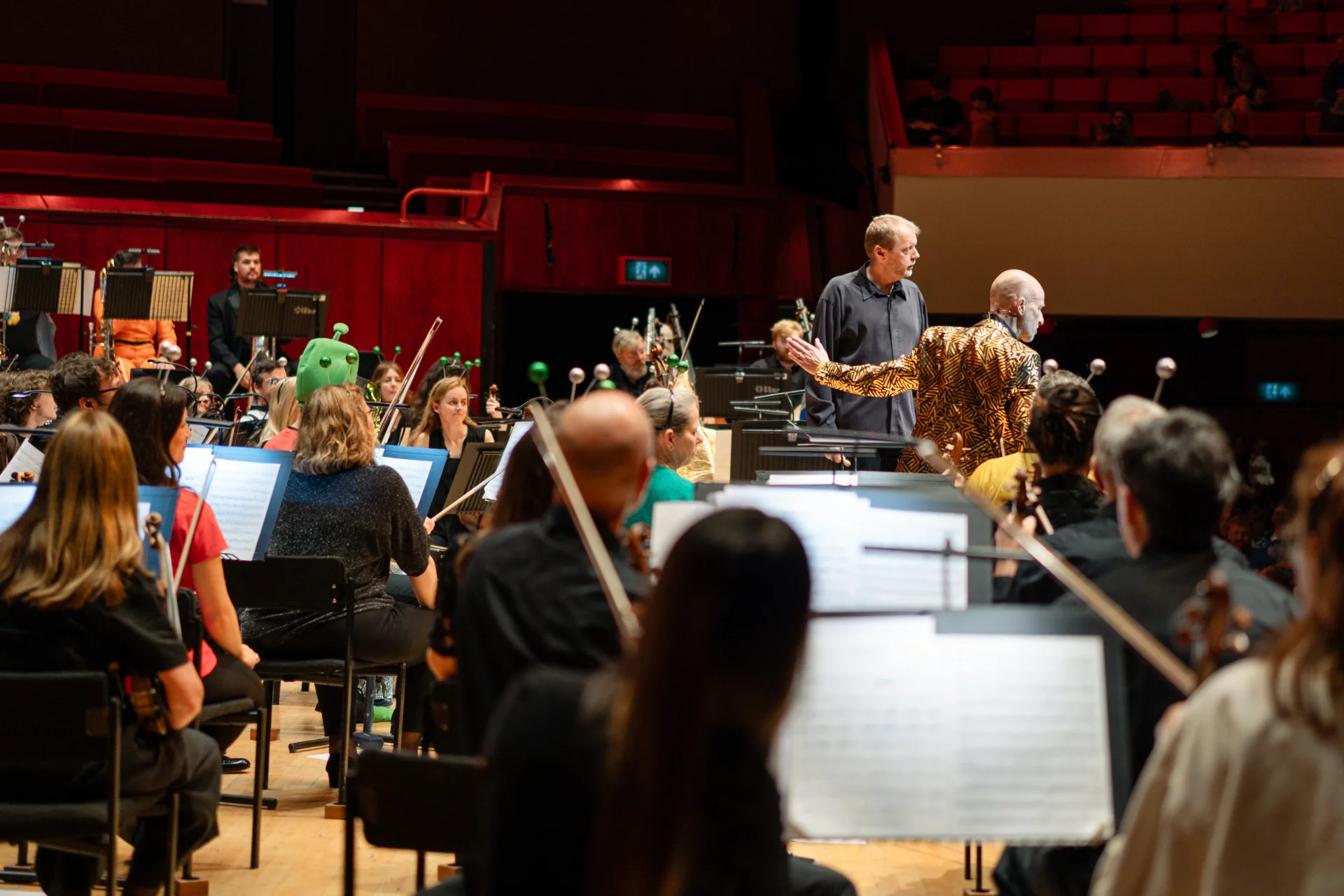 The presenter Tim Steiner at the front of the stage standing by the conductor and talking to the audience