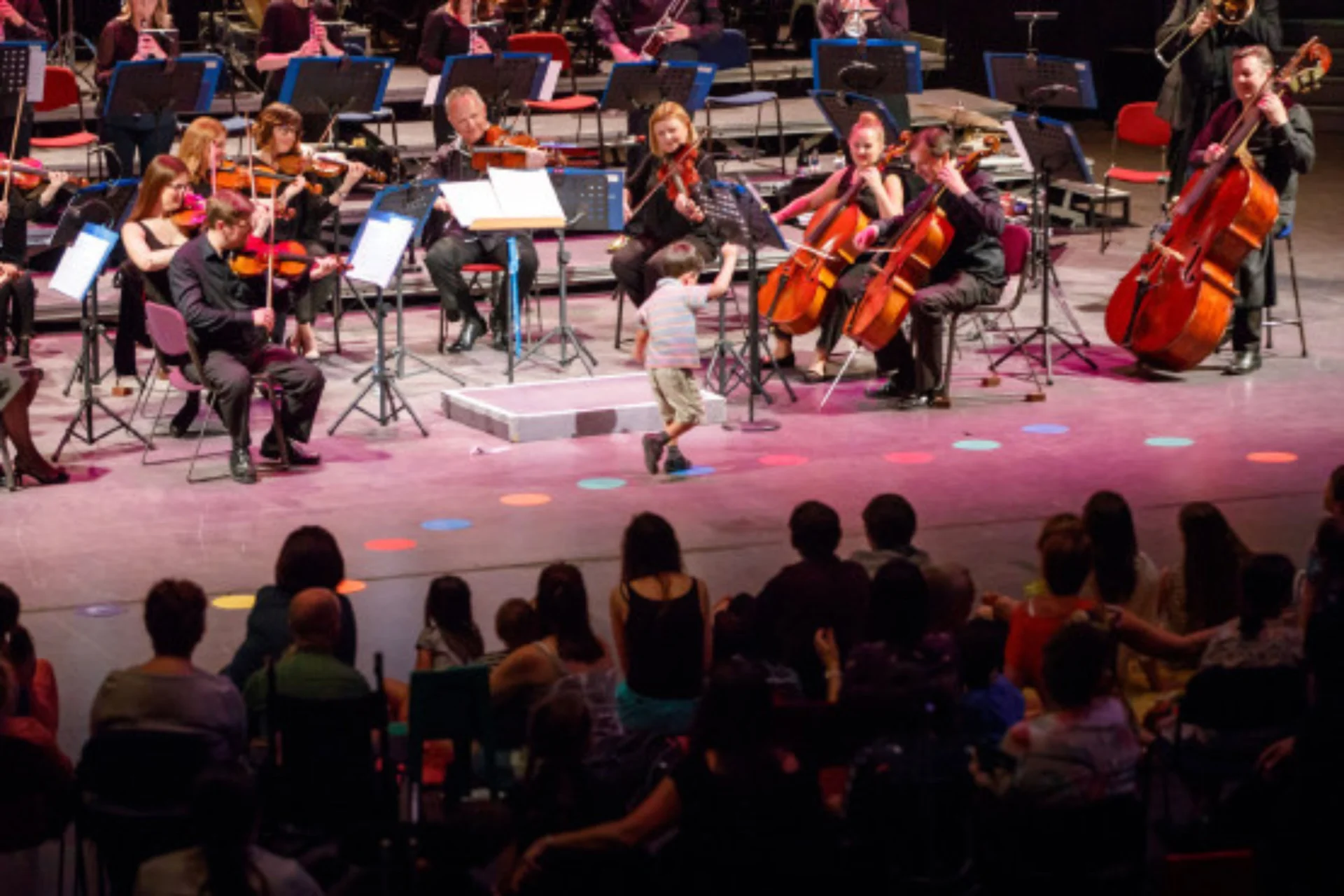 A child walks past the Royal Philharmonic Orchestra, hopping on coloured dots on the floor