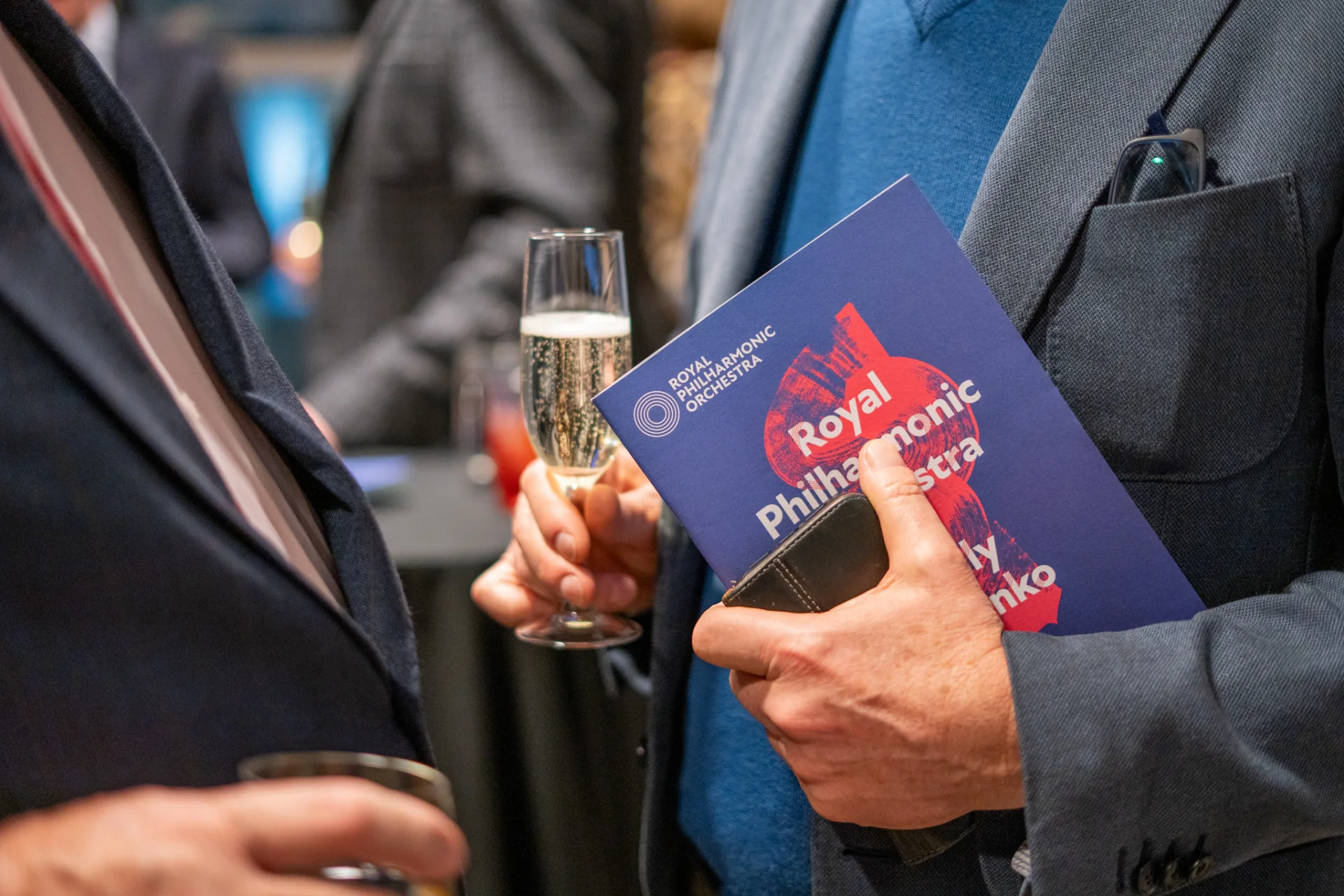 RPO patron holding a programme for the RPO's 2025-26 London Season and a glass of sparkling wine
