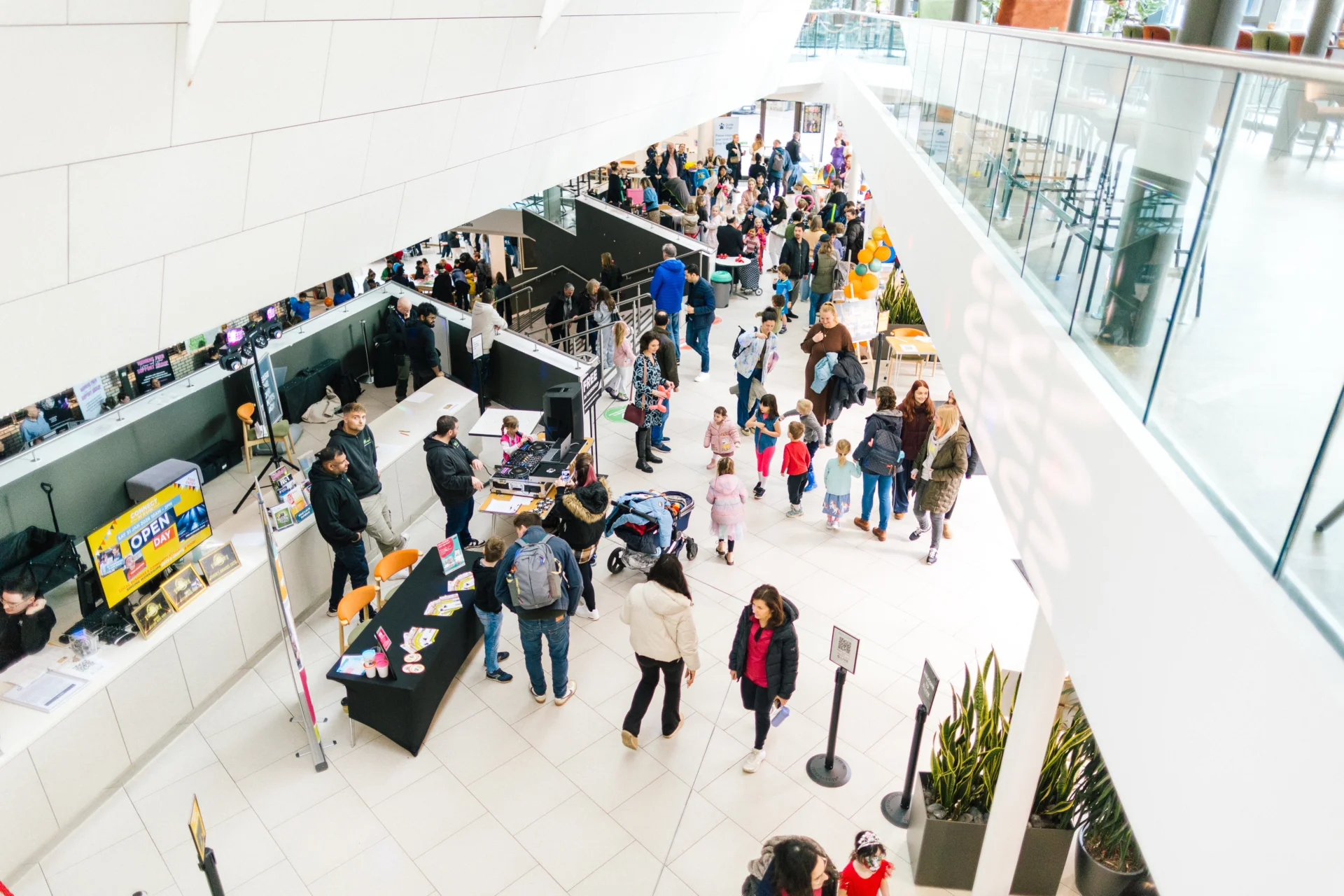 Shot of the foyer of G Live from the balcony above. Audience members enjoy the space and speak to the box office desk.