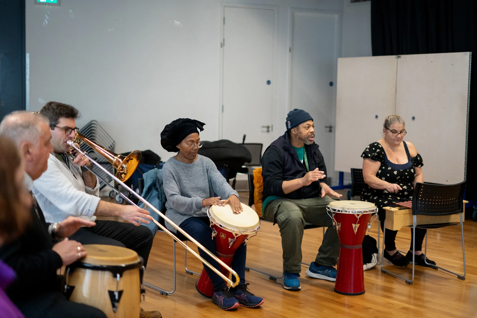 Sound Sanctuary participants playing percussive instruments in a circle together with an RPO trombonist