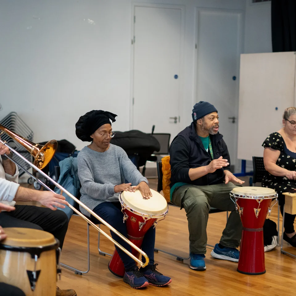 Sound Sanctuary participants playing percussive instruments in a circle together with an RPO trombonist