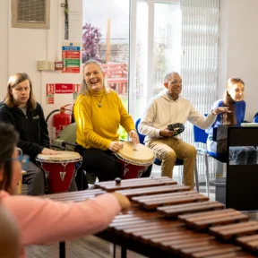 Sound Sanctuary participants playing xylophones and percussive instruments in a circle together