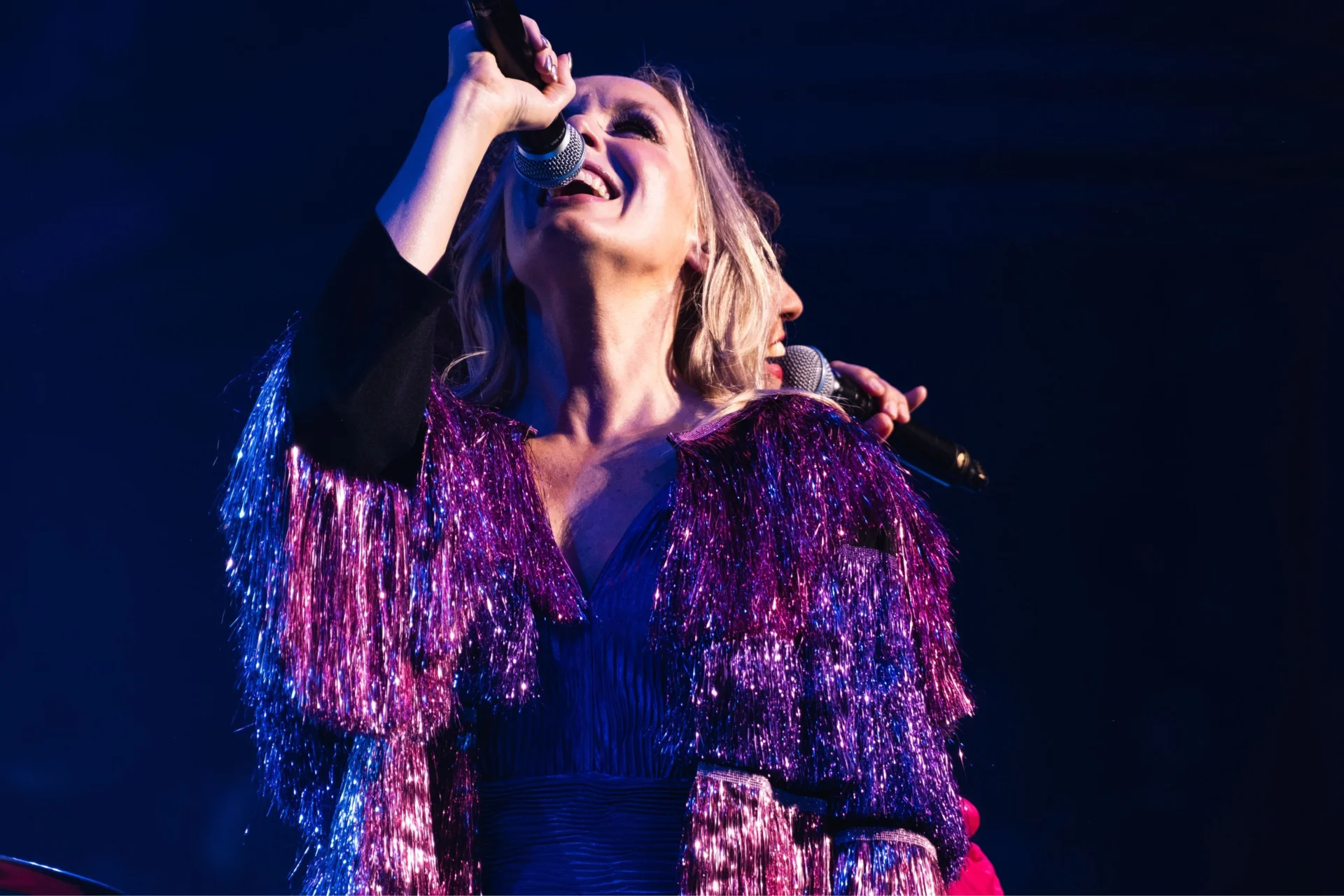 ABBAphonic vocalist sings into microphone wearing glittery purple flaires