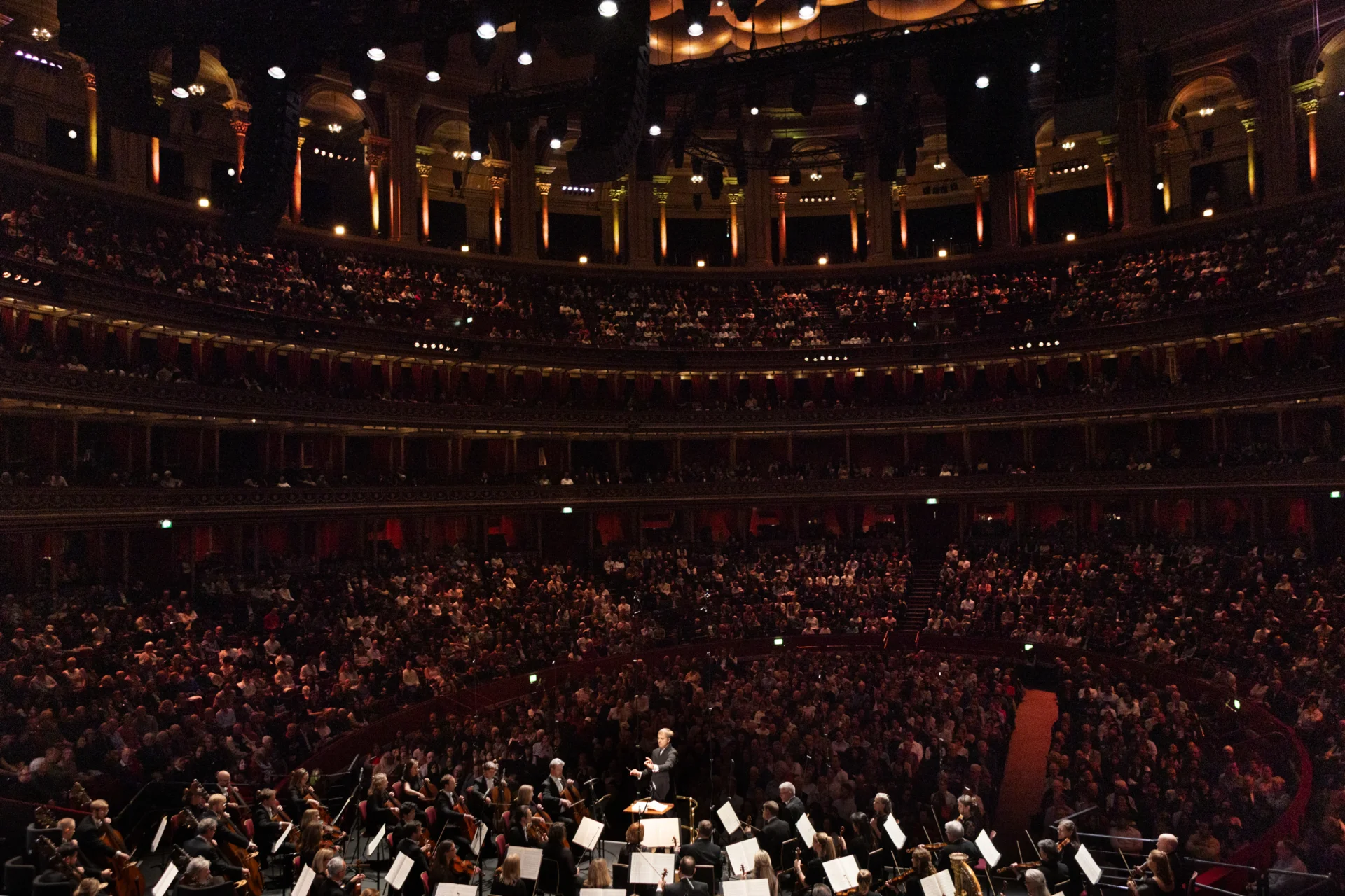 A wide shot from behind the Orchestra with the audience in the auditorium