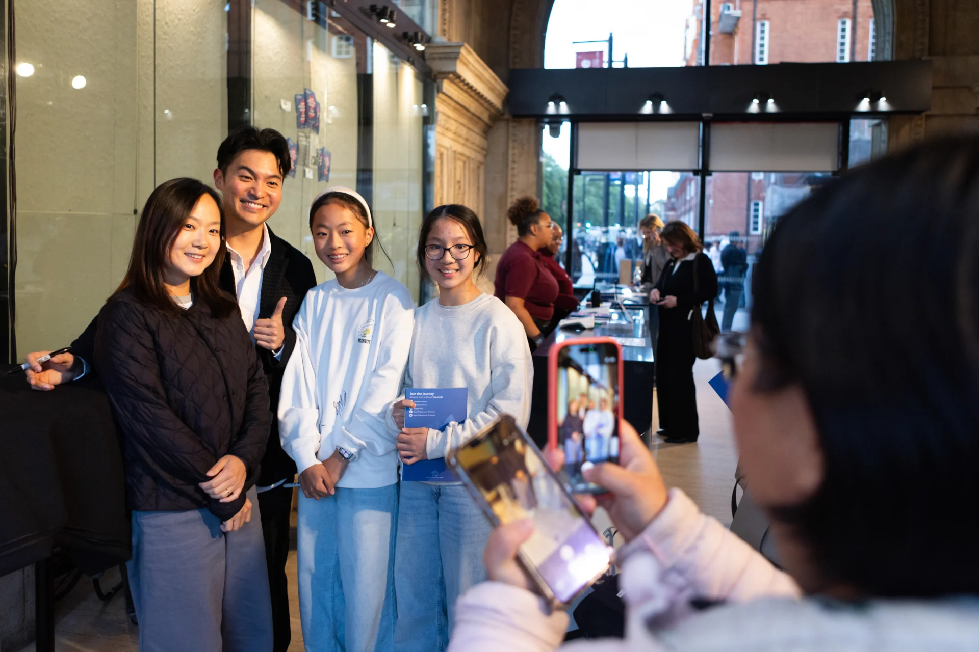 Ray Chen posing with fans as they have a photo taken in one of the Royal Albert Hall porches