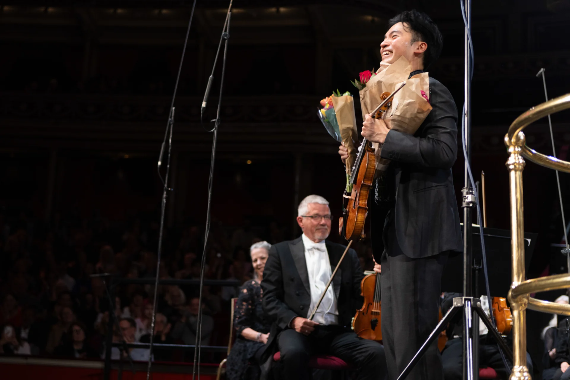 Ray Chen smiling as he holds bouquets of flowers