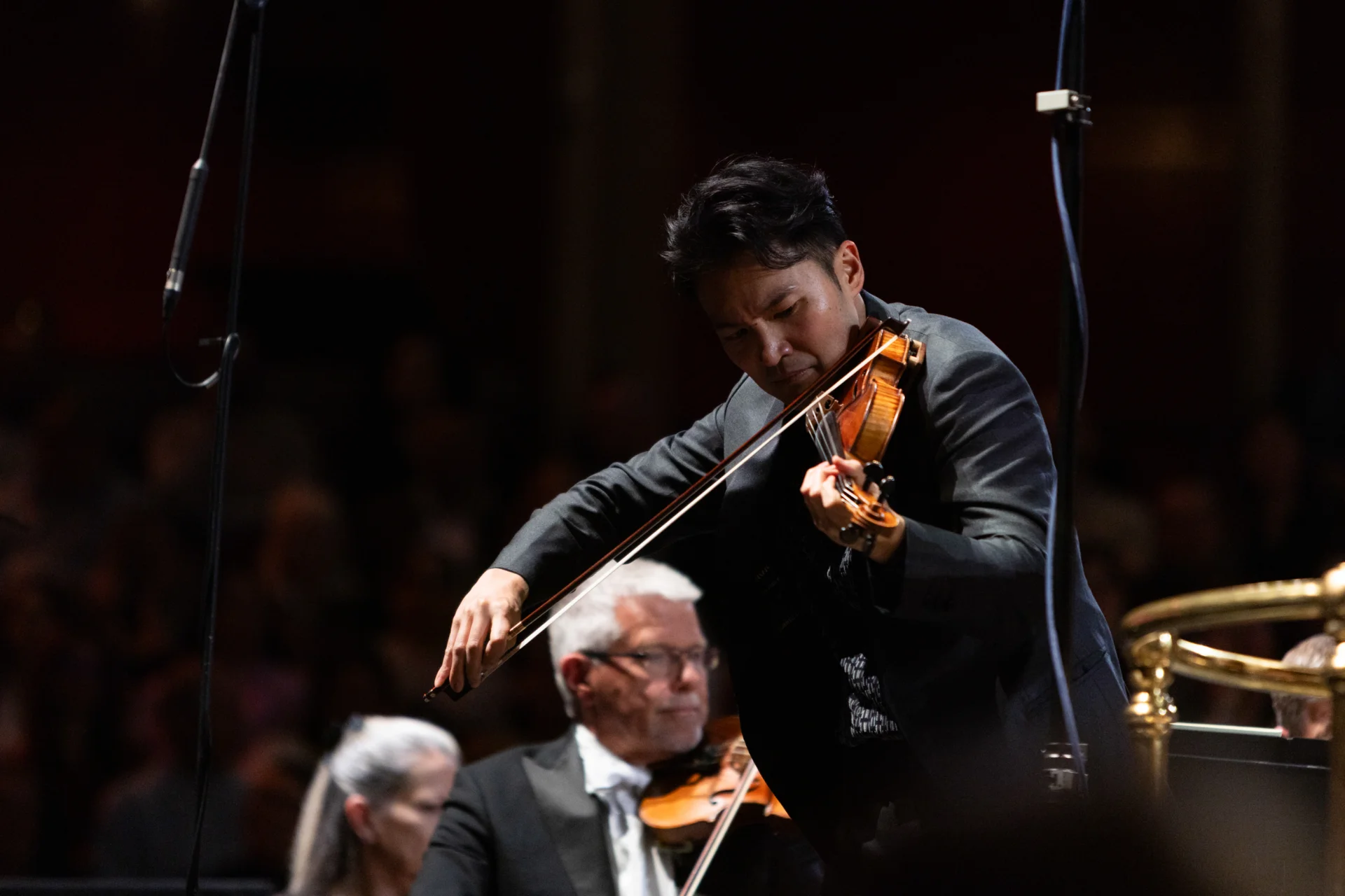 A close-up of Ray playing his violin and looking intently down at his instrument