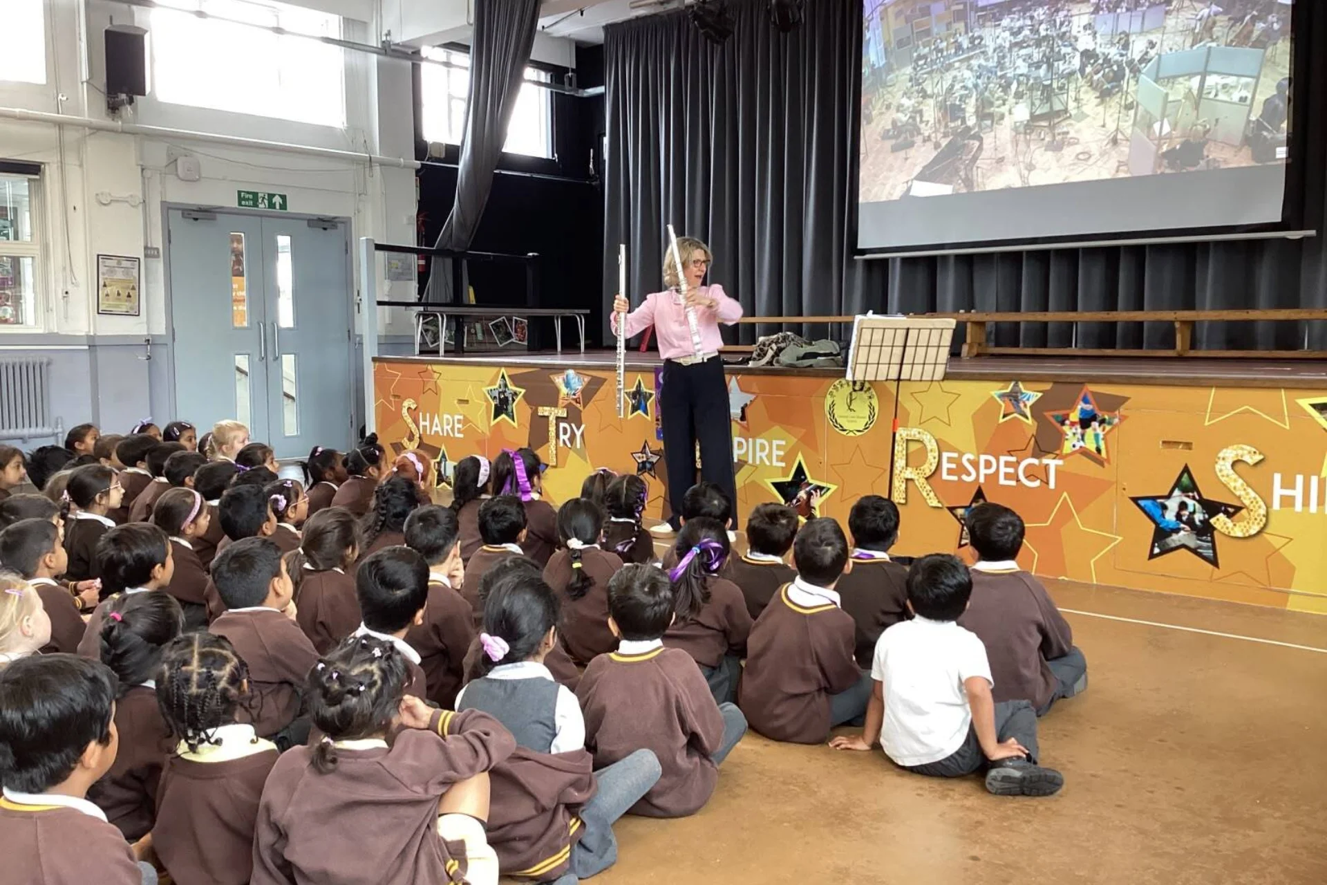 Joanna Marsh holding flute in front of seated students in school hall