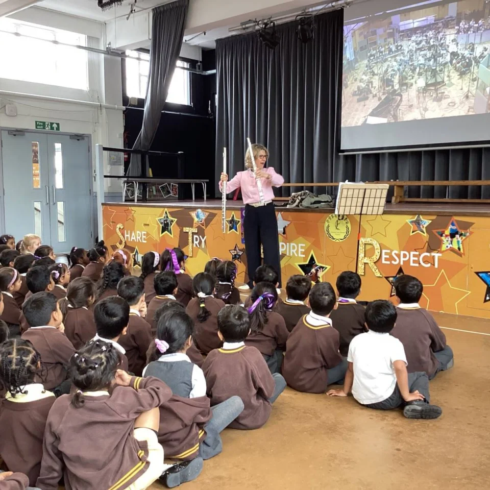 Joanna Marsh holding flute in front of seated students in school hall