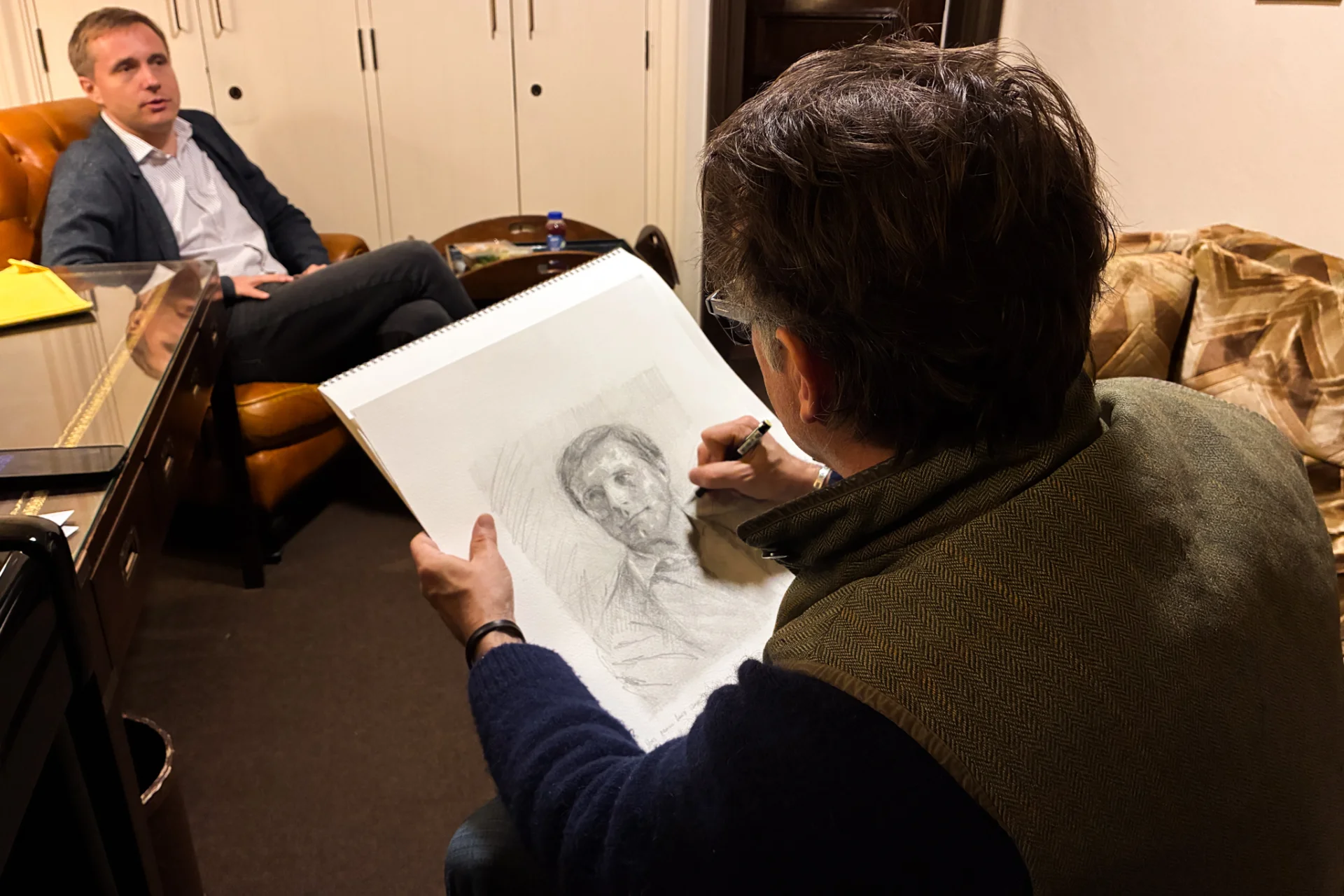 Artist Jeremy Houghton seated and sketching in pencil Vasily Petrenko, also seated