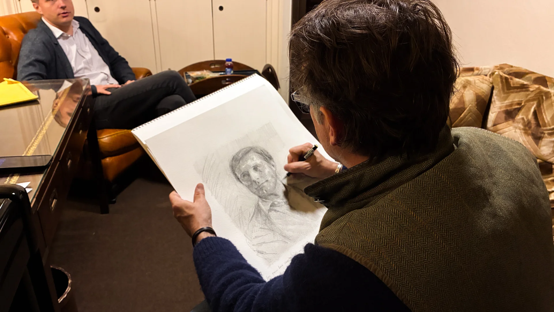 Artist Jeremy Houghton seated and sketching in pencil Vasily Petrenko, also seated