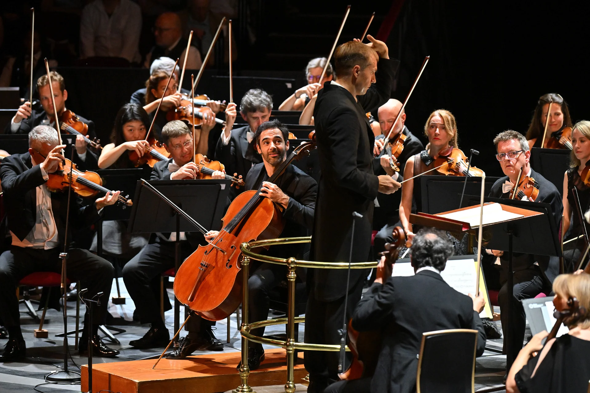 Pablo Ferrández holding his cello and looking up towards Vasily Petrenko