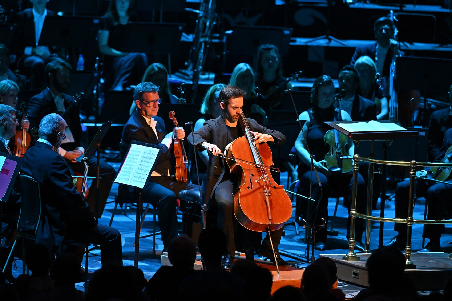 Pablo Ferrández playing the cello solo with the stage in dark blue lighting behind him