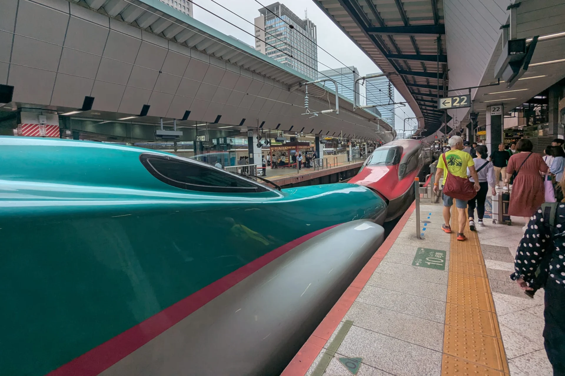 People walking along a platform with bullet trains