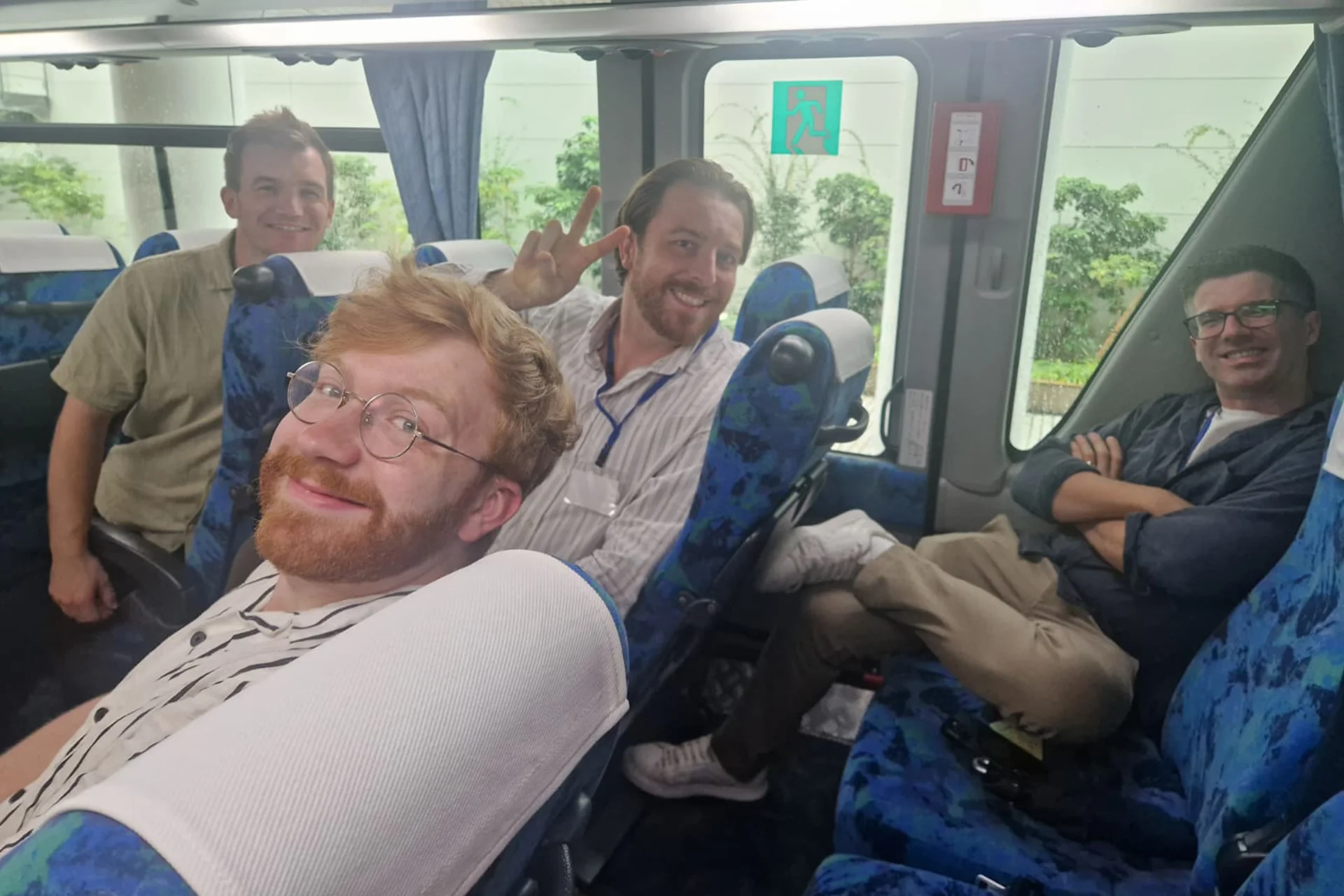 Four bass players smiling at the back of a bus