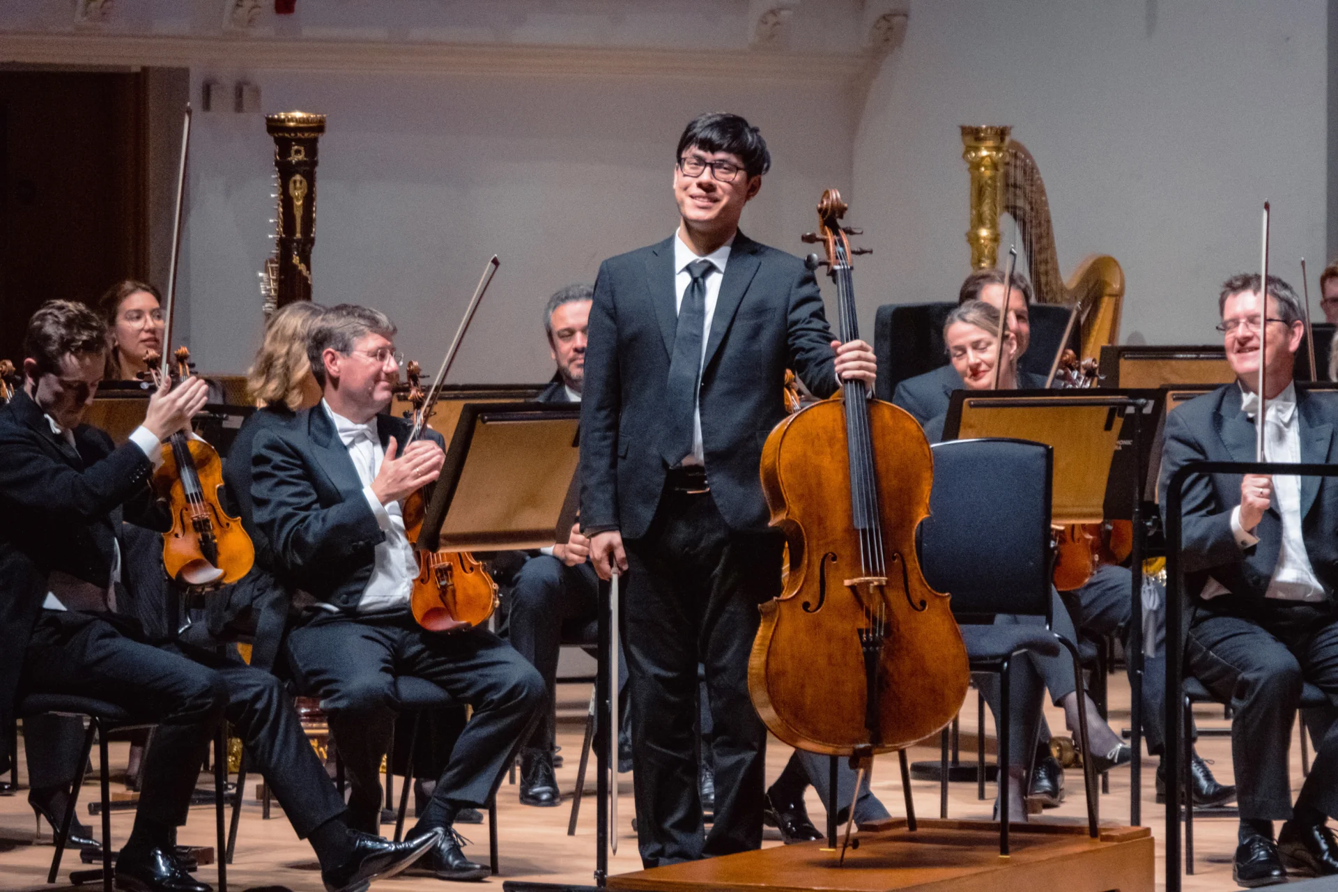 Zlatomir standing with his cello on stage in front of the Orchestra to receive applause
