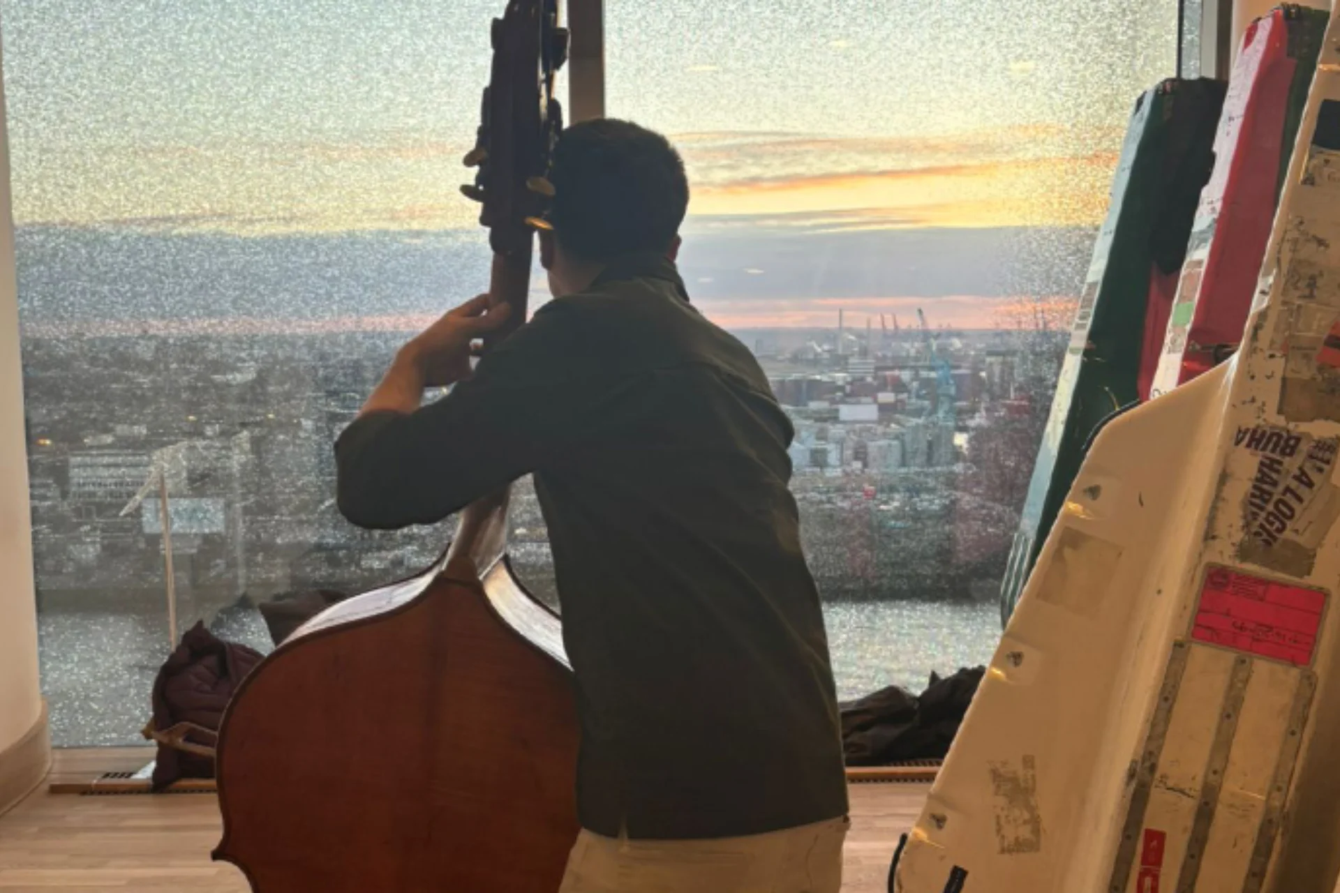 A double bass player practicing while looking out over a sunset in Hamburg