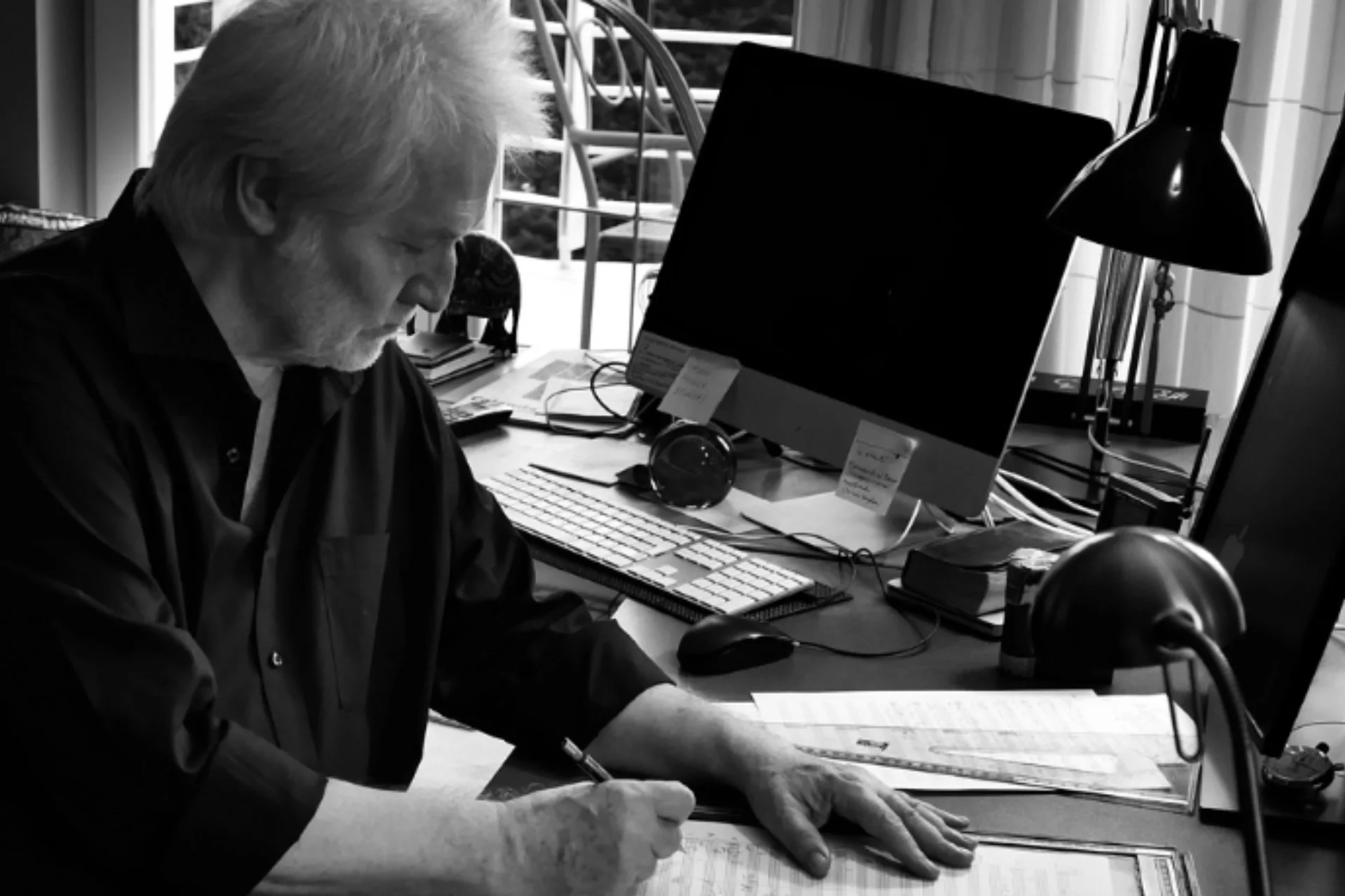 P\u00e9ter E\u00f6tv\u00f6s sitting at his desk and writing on a score