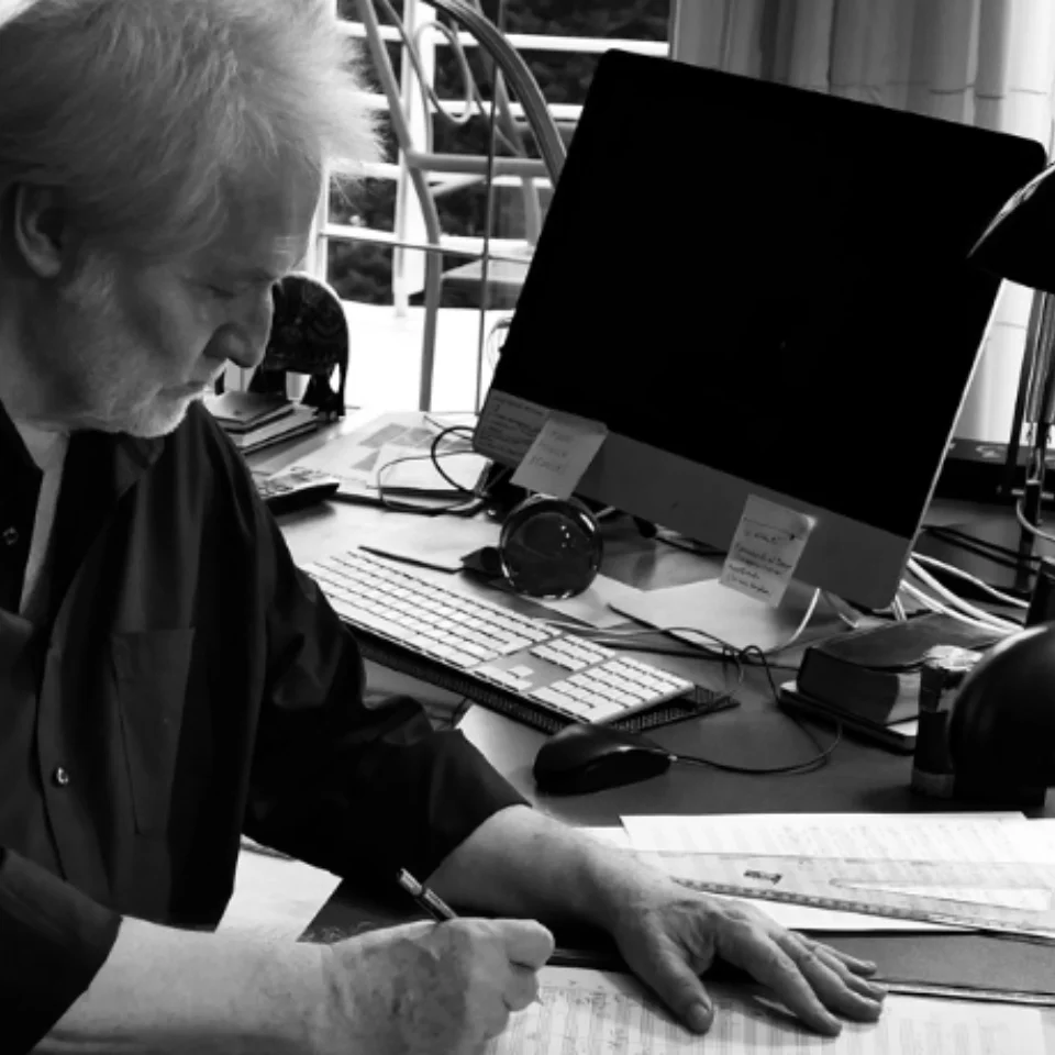 P\u00e9ter E\u00f6tv\u00f6s sitting at his desk and writing on a score