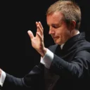 Vasily Petrenko conducting with his hands raised in front of him and his eyes closed