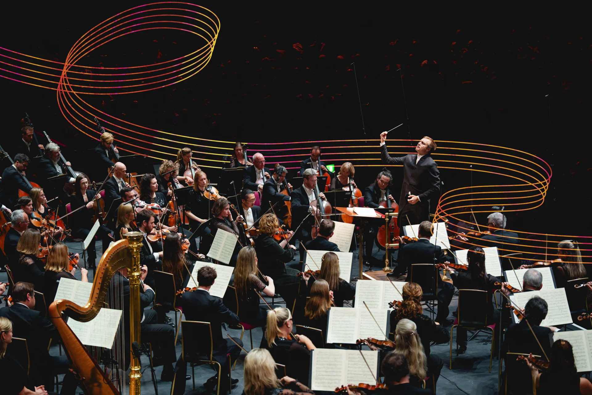 Vasily Petrenko conducting the Orchestra at the Royal Albert Hall. Coloured wavy lines weave behind the Orchestra.