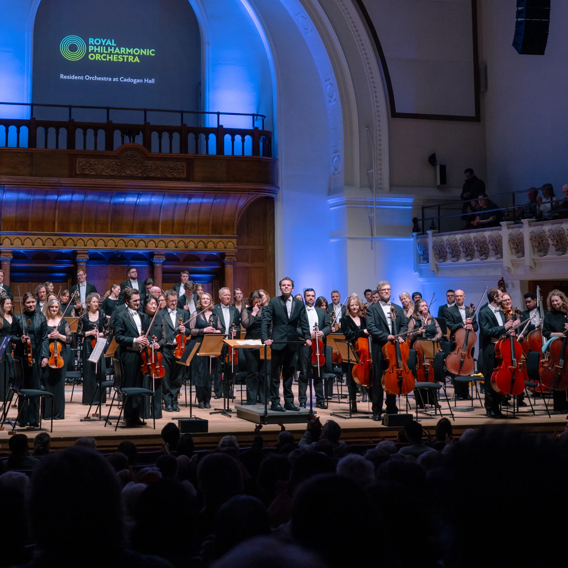 The RPO standing on stage with conductor Adam Hickox on stage at Cadogan Hall