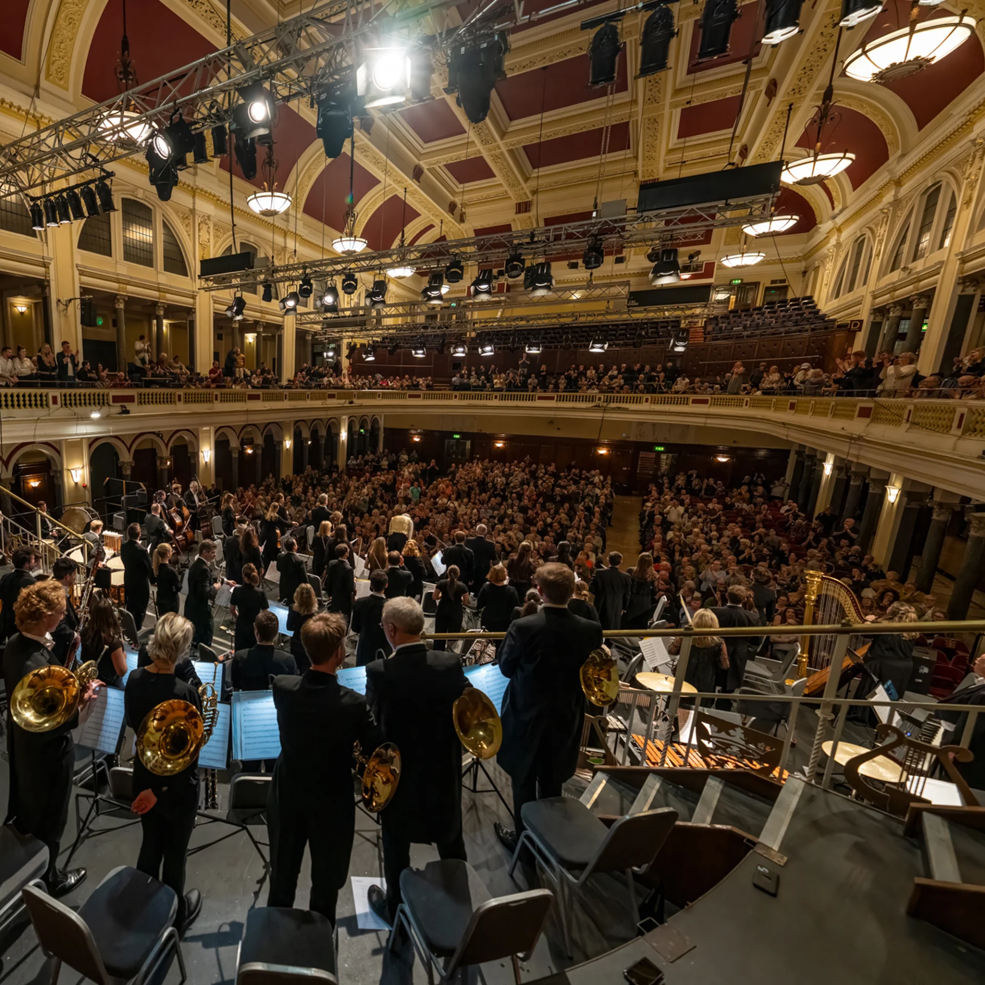 A wide fisheye lens shot from behind the Orchestra as they stand on stage in Hull City Hall for applause