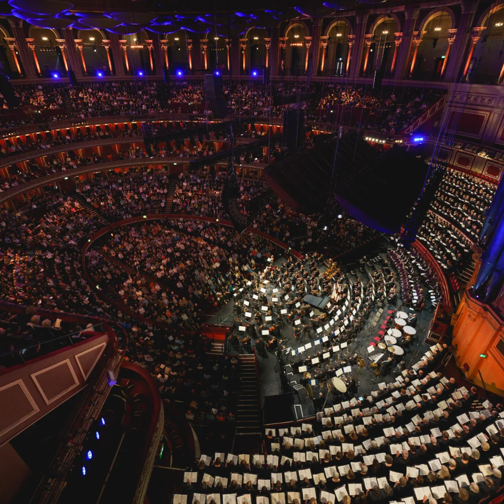 Wide shot of the inside of the Royal Albert Hall during a Royal Philharmonic Orchestra Performance, showing the full audience and stage in the iconic round venue.
