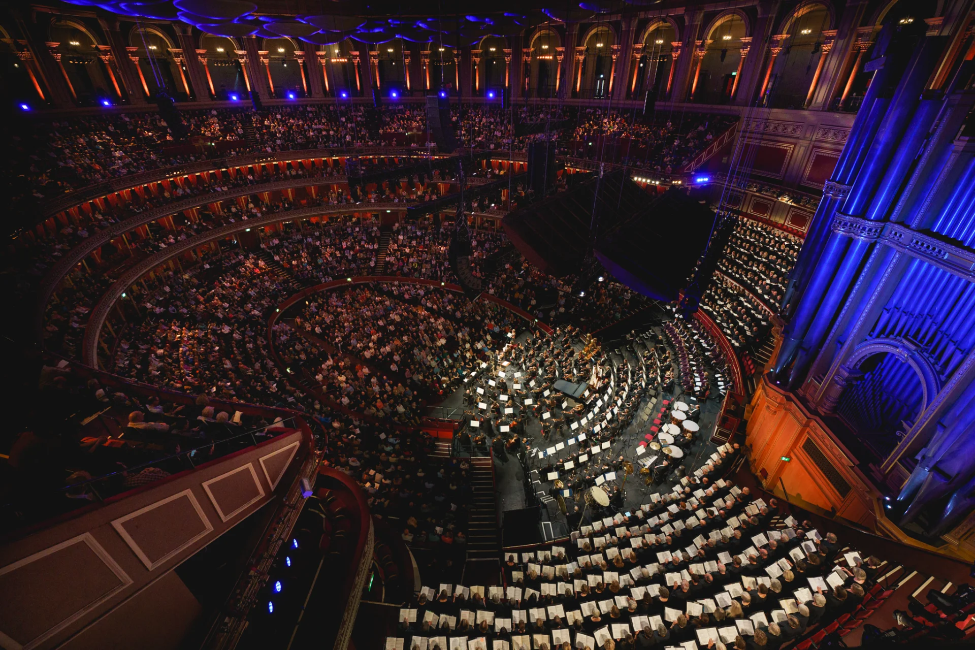Wide shot of the inside of the Royal Albert Hall during a Royal Philharmonic Orchestra Performance, showing the full audience and stage in the iconic round venue.