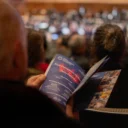 Close up of an audience member at the Royal Festival Hall, looking through the programme of a Royal Philharmonic Orchestra performance
