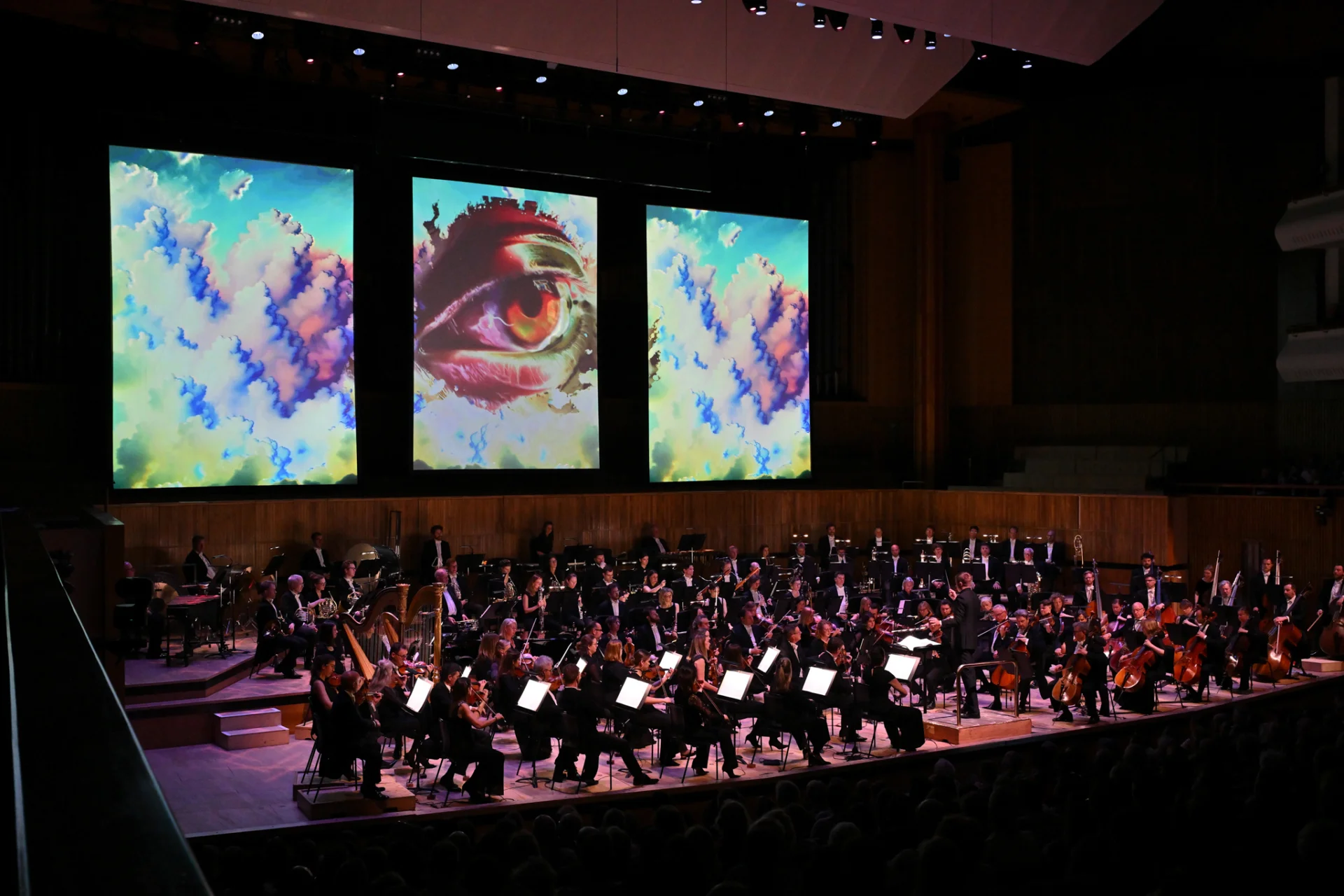 The RPO on stage at Royal Festival Hall with large projections of eyes on screen behind stage