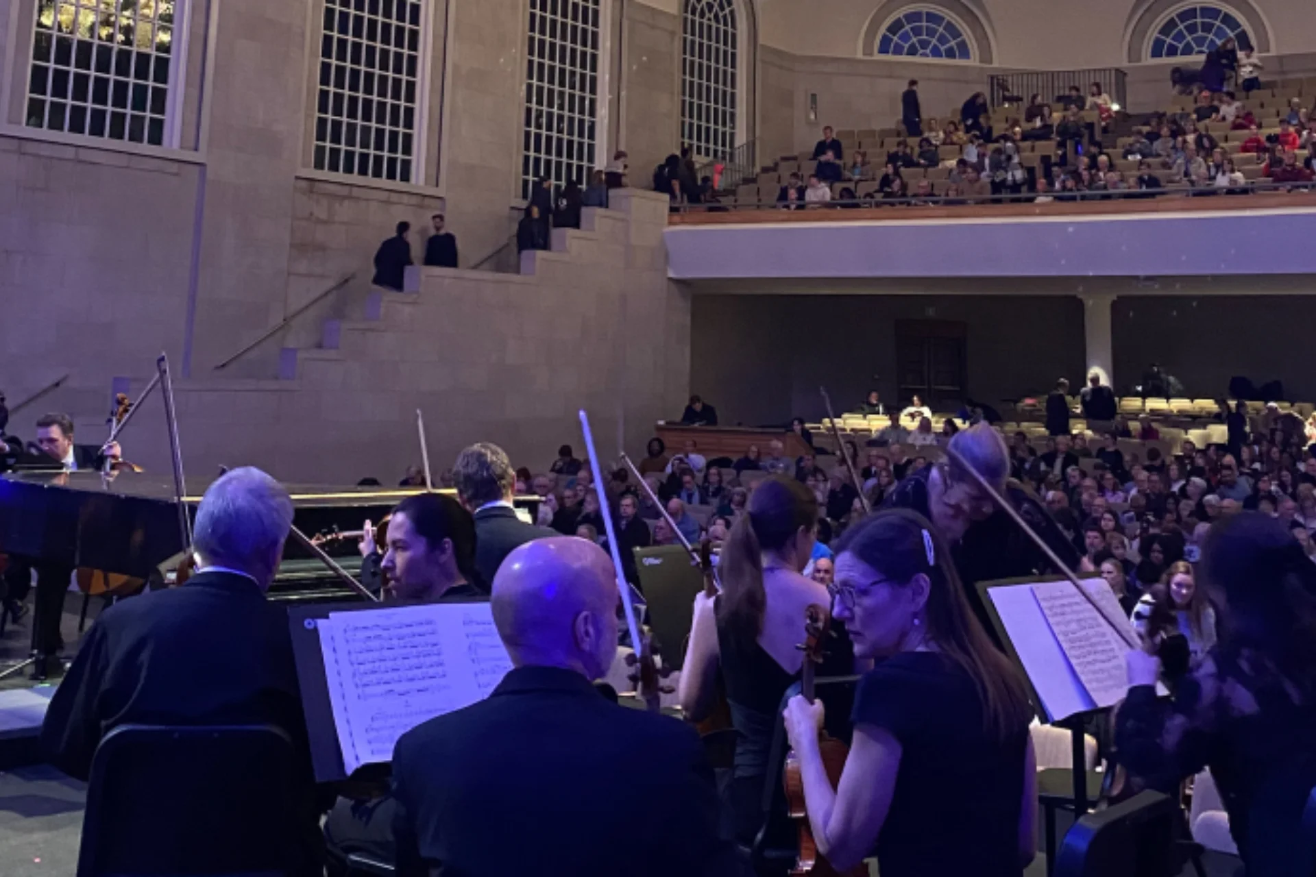 An Orchestra playing in front of an audience in a large concert hall